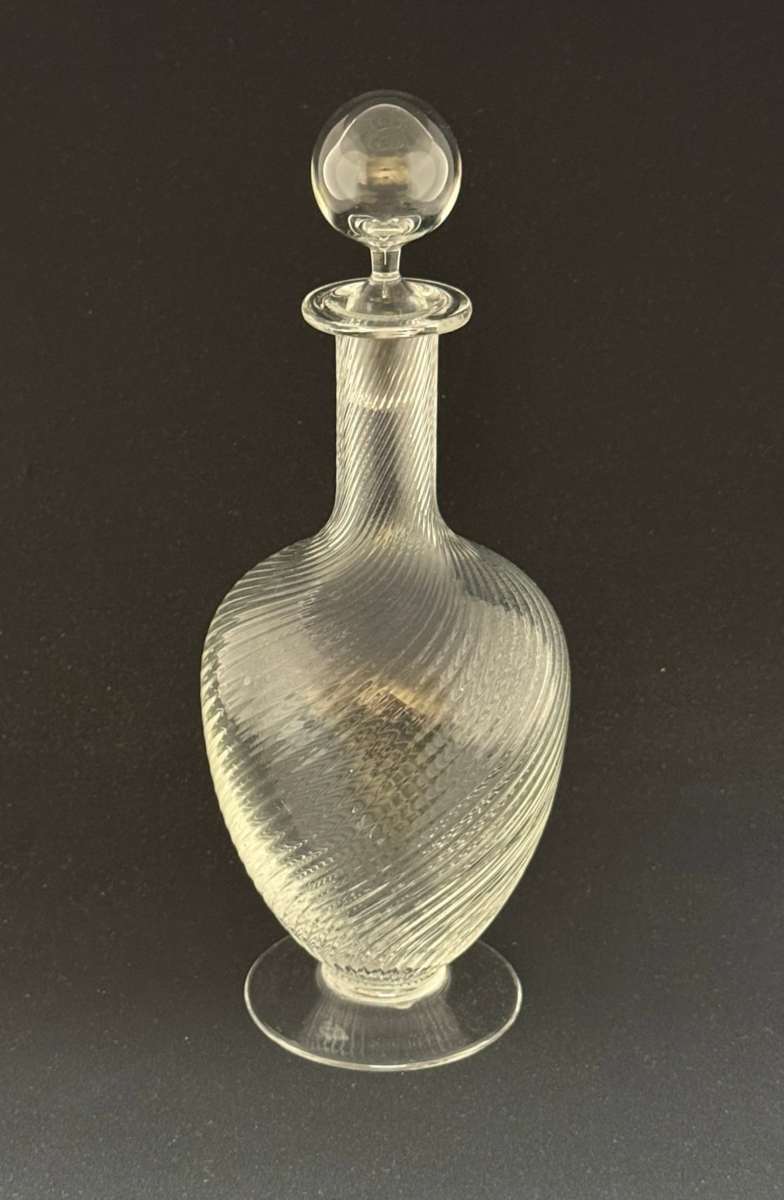 Tiffany Swirled Footed Decanter: Tiffany and Company footed decanter in a swirl pattern, signed Tiffany Co. 12 1/2" ht. CONDITION: no chips, cracks, repairs, or material defects found, Jaremos attempts to call any material flaw that 