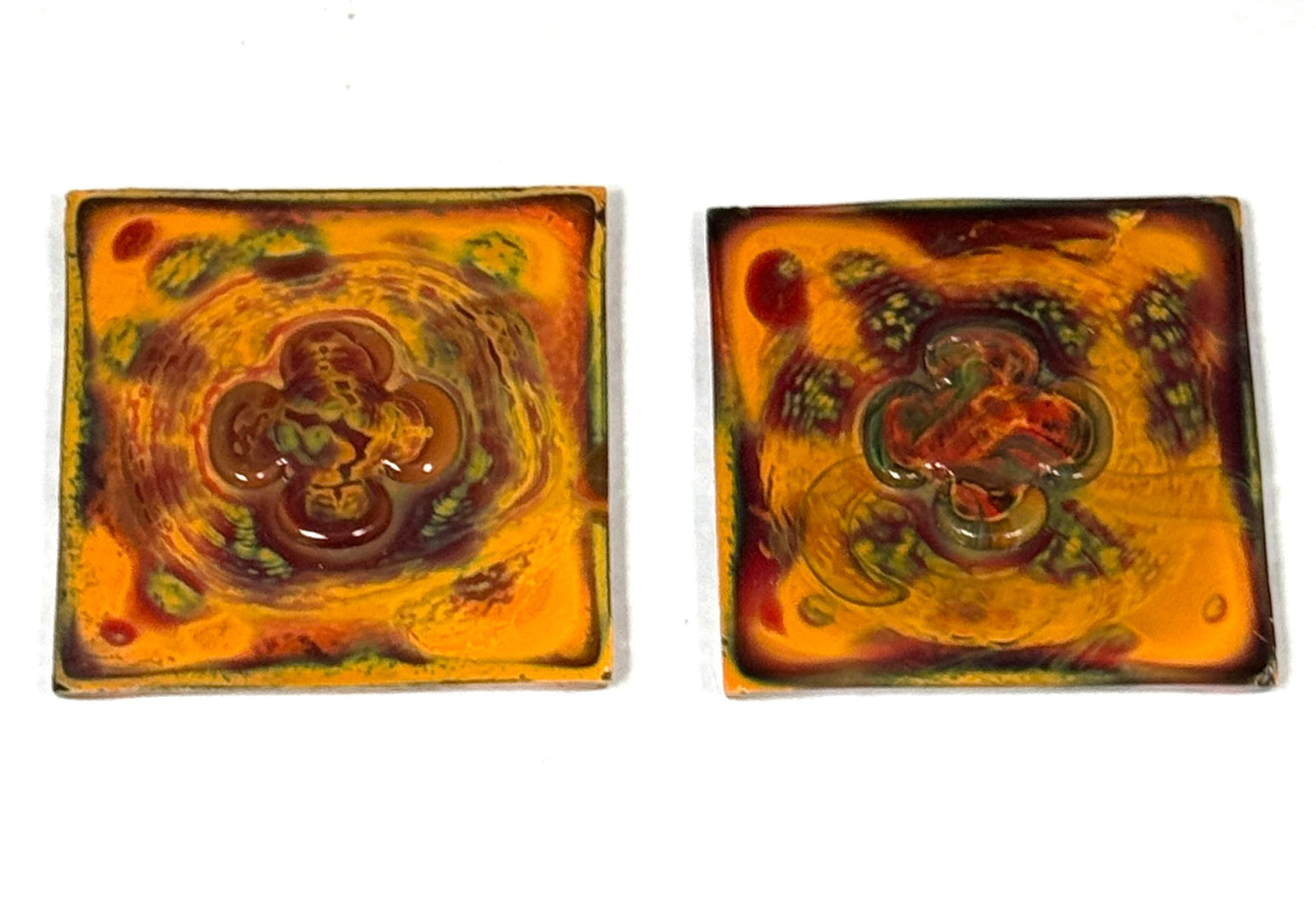 2 Variegated Tiffany Tiles: 2 green, yellow and brown variegated Tiffany tiles with flower in center, unsigned; 3". CONDITION: Tiffany tiles have propensity to chip, expect minor flakes, we have called any major chips. For more 