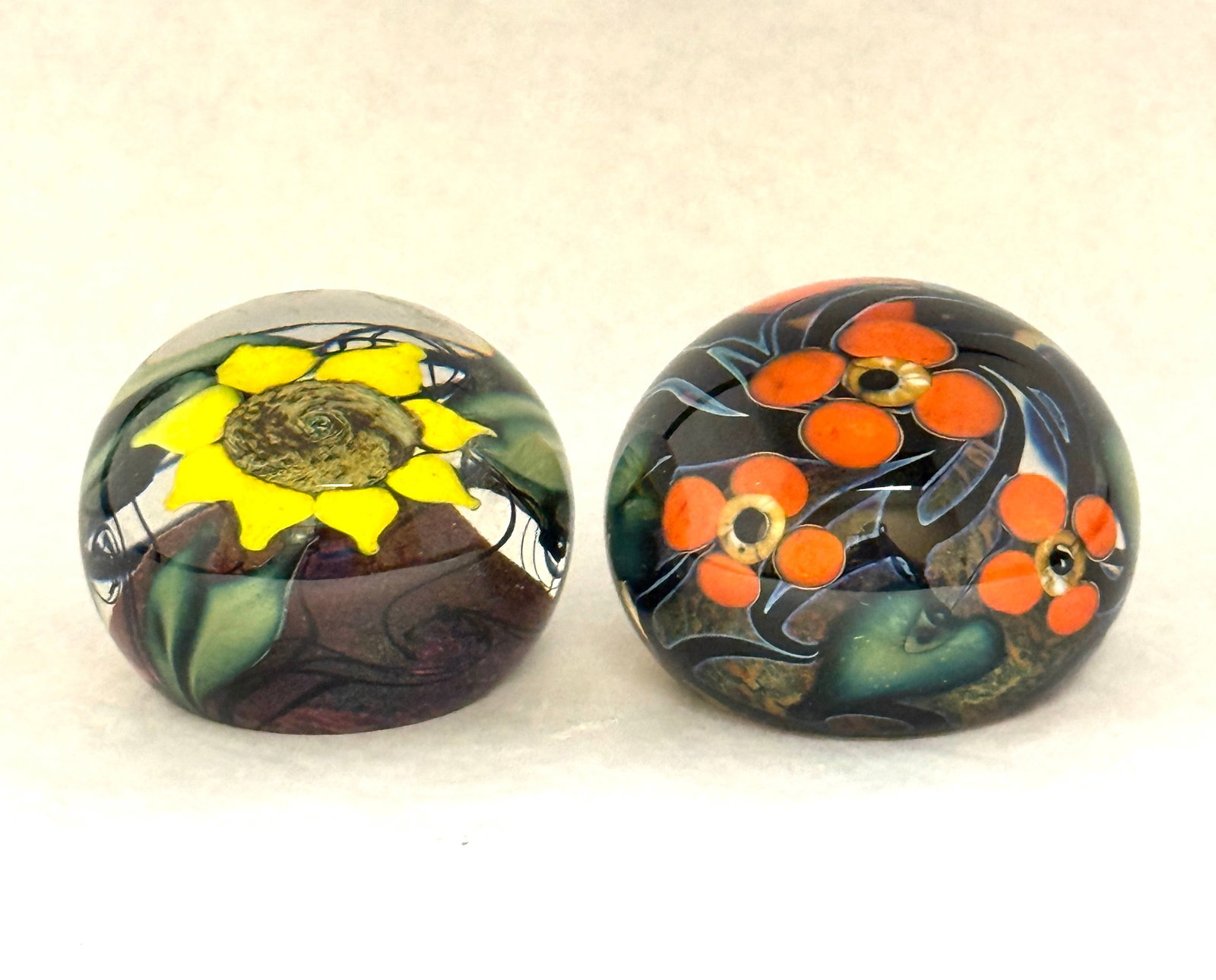 2 Lotton Studio Paperweights: 2 Lotton Studio paperweights created by Tony Navaratte one Multi Flora with orange flowers, and the other with a large yellow sunflower, both signed, largest 3" wide. CONDITION: no chips, cracks,