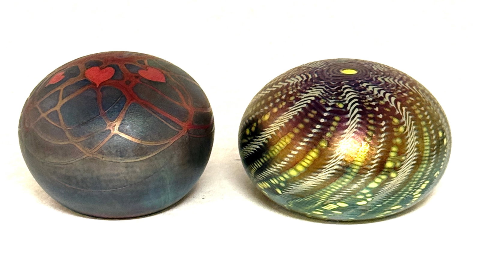 2 Lundberg Paperweights: 2 Lundberg paperweights including an iridescent blue with swirled design signed Lundberg 73, together with a dark blue with red hearts and vines signed Lundberg 78, largest 3 1/4" wide. CONDITION: no
