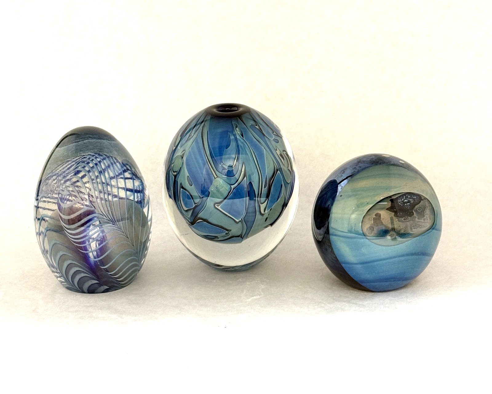 3 Eickholt Paperweights: 3 Eickholt paperweights in blue one with an aventurine peacock feather one attributed moon landscape and the third in a blue swirl, all signed, largest 4" ht. CONDITION: no chips, cracks, repairs, or