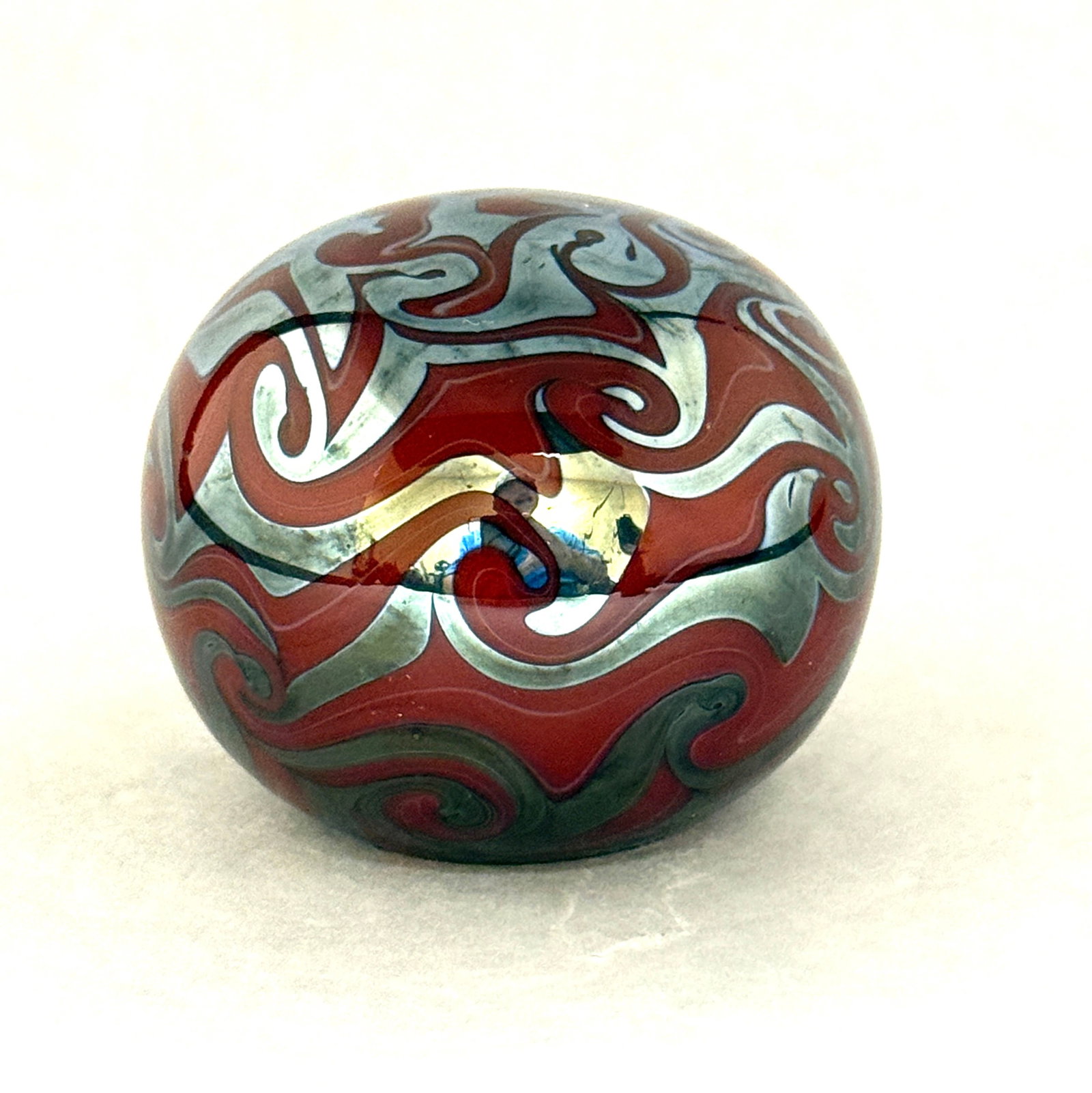 Steve Lundberg Paperweight: Steve Lundberg red paperweight with a platinum blue coil design, signed Steven Lundberg 1984, 3" wide. CONDITION: no chips, cracks, repairs, or material defects found, Jaremos attempts to call any