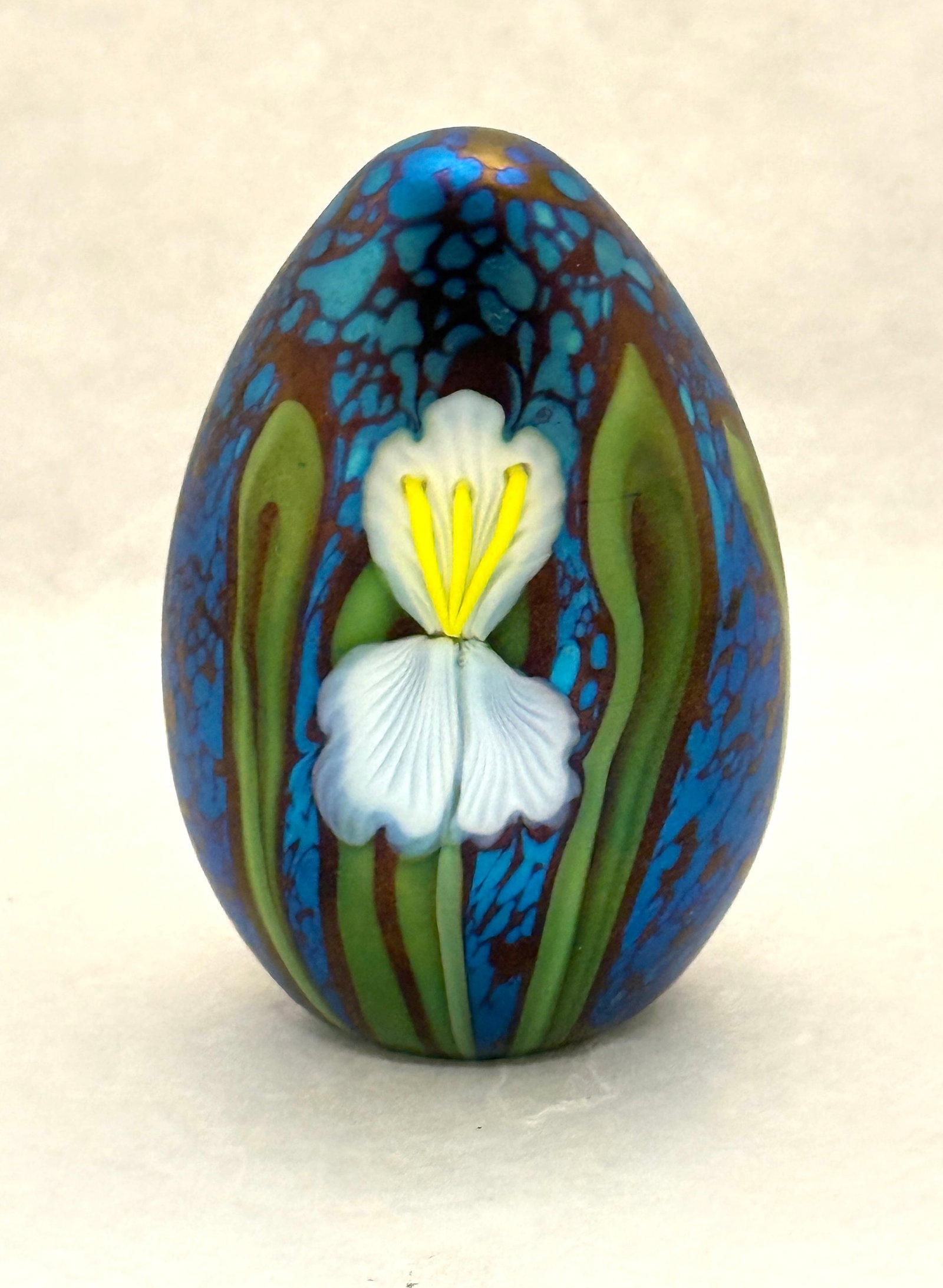 Orient and Flume Paperweight: Orient and Flume egg form paperweight in iridescent blue decorated with a white iris includes gift box and bag, signed Alexander Orient and Flume, 4" ht. CONDITION: no chips, cracks, repairs, or