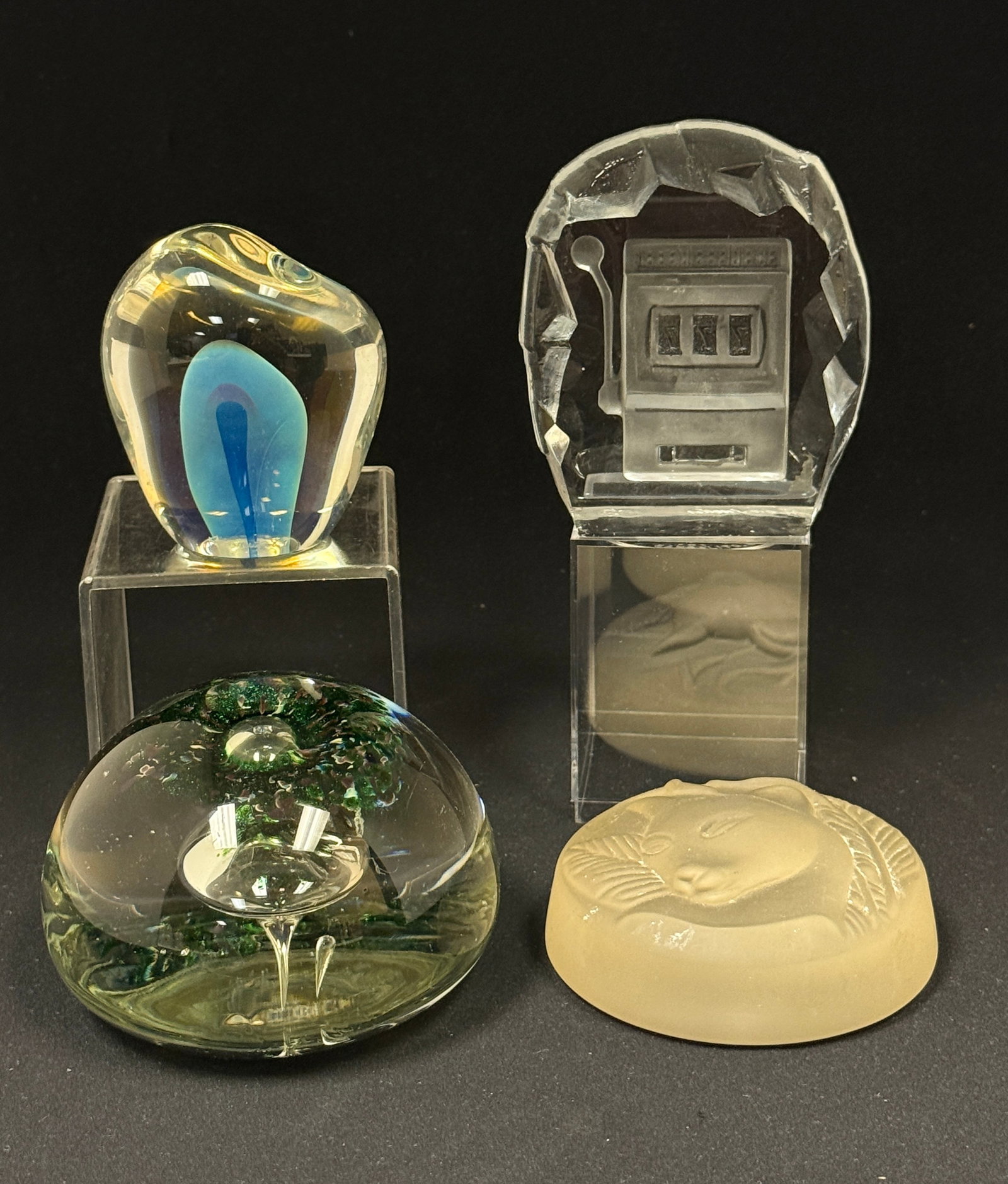 4 Glass Paperweights: 4 glass paperweights including: a Nybro Crystal with etched slot machine interior signed Nybro Sweden, a frosted with cat head unsigned, a clear dome shaped with blue and pink dome interior signed