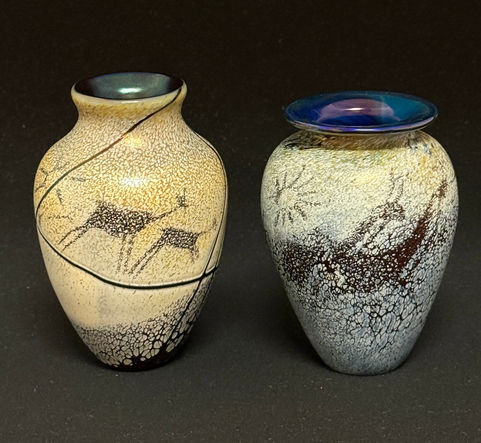 2 Rick Satava Glass Vases: 2 Rick Satava Petroglyph glass vases one in cream and one in blue with cave drawings, both signed 4" ht. CONDITION: no chips, cracks, repairs, or material defects found, Jaremos attempts to call any m