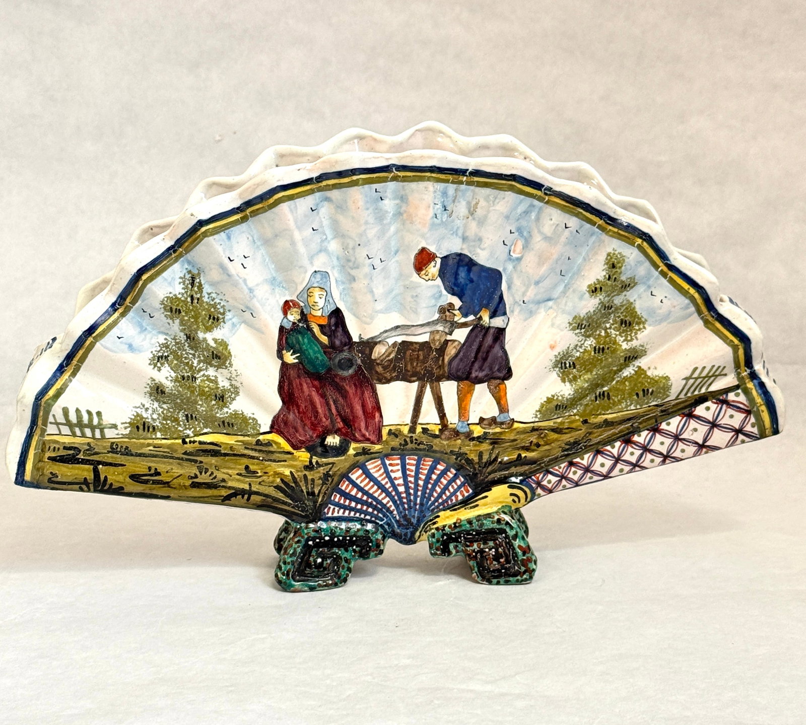 HB only Fan Vase: HB only circa 1883-1904, Eventail fan vase decorated with a Breton working with Bretonne and baby looking on, reverse with courting couple, signed HB, ht 6". CONDITION: Quimper has propensity to have 