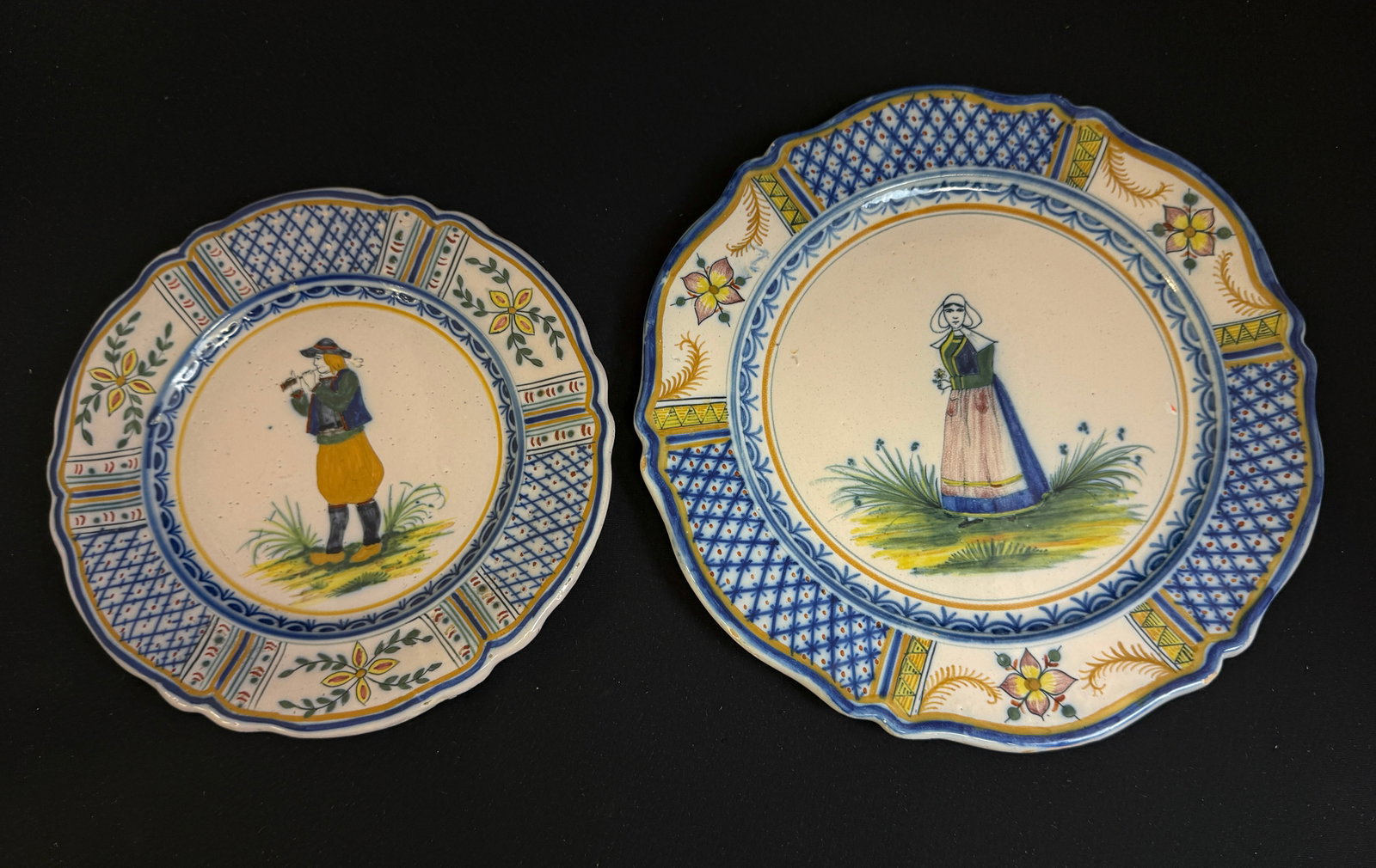 2 HR Quimper Plates: 2 HR Quimper plates, a Breton playing bombarde; diameter 7 3/4" and a Bretonne holding a flower; diameter 9 1/5". Both with Crosille border. CONDITION: Quimper has propensity to have minor chips,