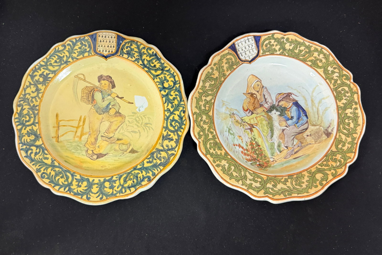 2 Porquier Beau Plates: 2 Porquier plates "Faucheur" Reaper, young boy, Blason of Brittany; diameter 9 1/4", and a Mother, son, and dog, Blason of Brittany, diameter 9". CONDITION: Restoration to one plate. Quimper has