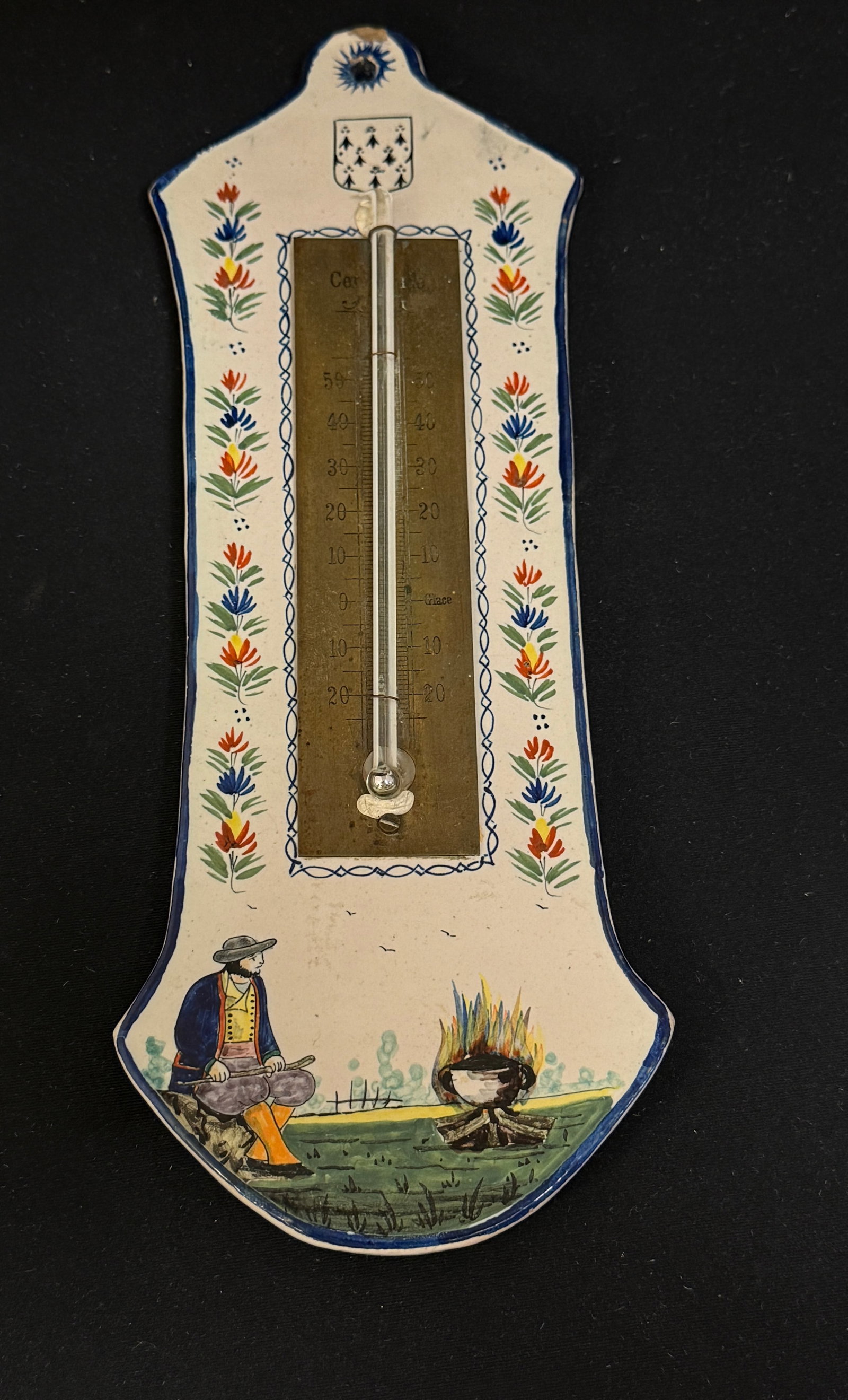 Rare HB Thermometer: Rare HB thermometer in centigrade, Blasen of Brittany, a la touch? sprays and a Bretonne sitting by a kettle; length 11 1/4" circa 1883-1904. CONDITION: chip on top from hanger. Quimper has