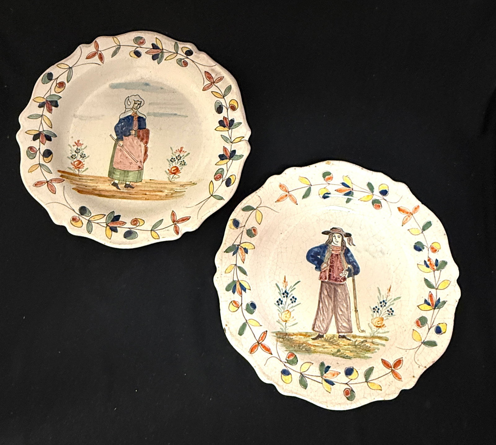 2 Malicorne Plates: 2 Malicorne plates including a marked PBx of a Bretonne holding a rod together with a Breton with walking stick hanging from his arm, diameter 9 1/2" circa 1895-1920. CONDITION: Quimper has