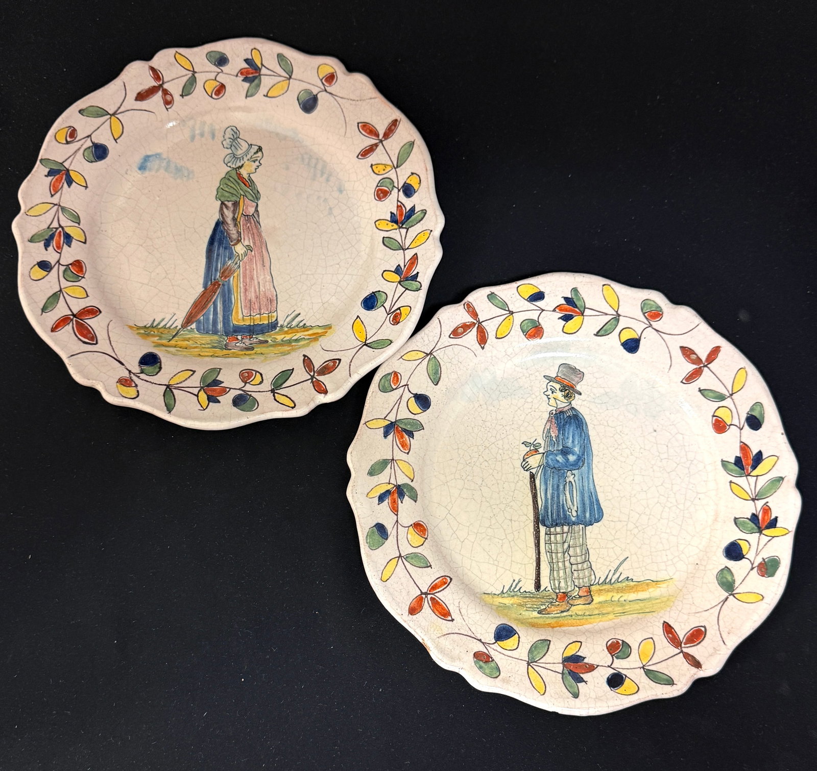 2 Malicorne Plates: 2 Malicorne plates one with a Gentleman carrying a walking stick and an apple together with a Bretonne carrying an umbrella, diameter 9 1/2 circa 1895-1920 CONDITION: Quimper has propensity to have
