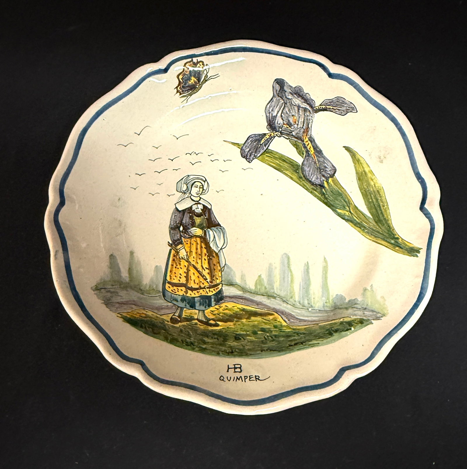 HB Quimper Botanical Plate: HB Quimper botanical plate with Bretonne and flock of seagulls and an iris stem and butterfly; diameter 10 1/4" circa 1900-1930. CONDITION: Quimper has propensity to have minor chips, glaze loss/wear