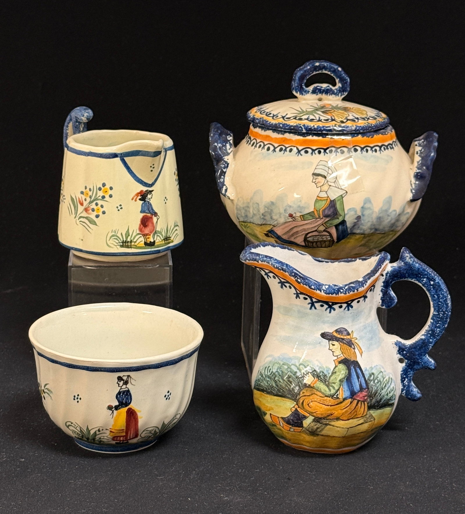 4 HenRiot Quimper Items: 4 HenRiot Quimper items including 2 sugar bowls and 2 creamers, largest set decorated with seated Bretons and decorated with sponging, ajonc, and bruyere, the other have Breton figures and decorated