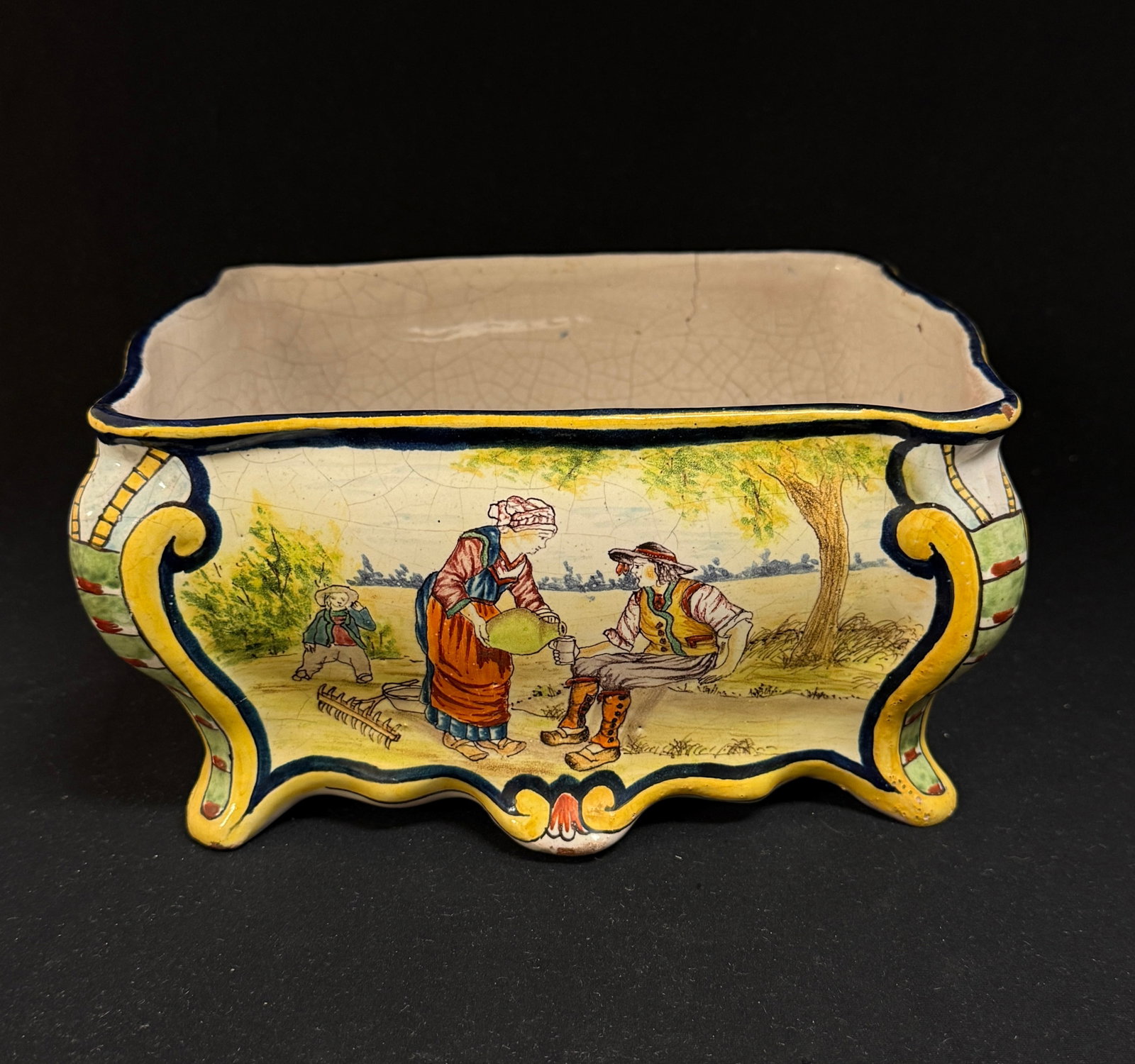 Malicorne Footed Jardiniere: Malicorne commode form footed jardiniere with 4 intricately painted scenes: parents and babies, grandparents and granddaughter, Breton farmers enjoying a drink, and parents listening to son read a