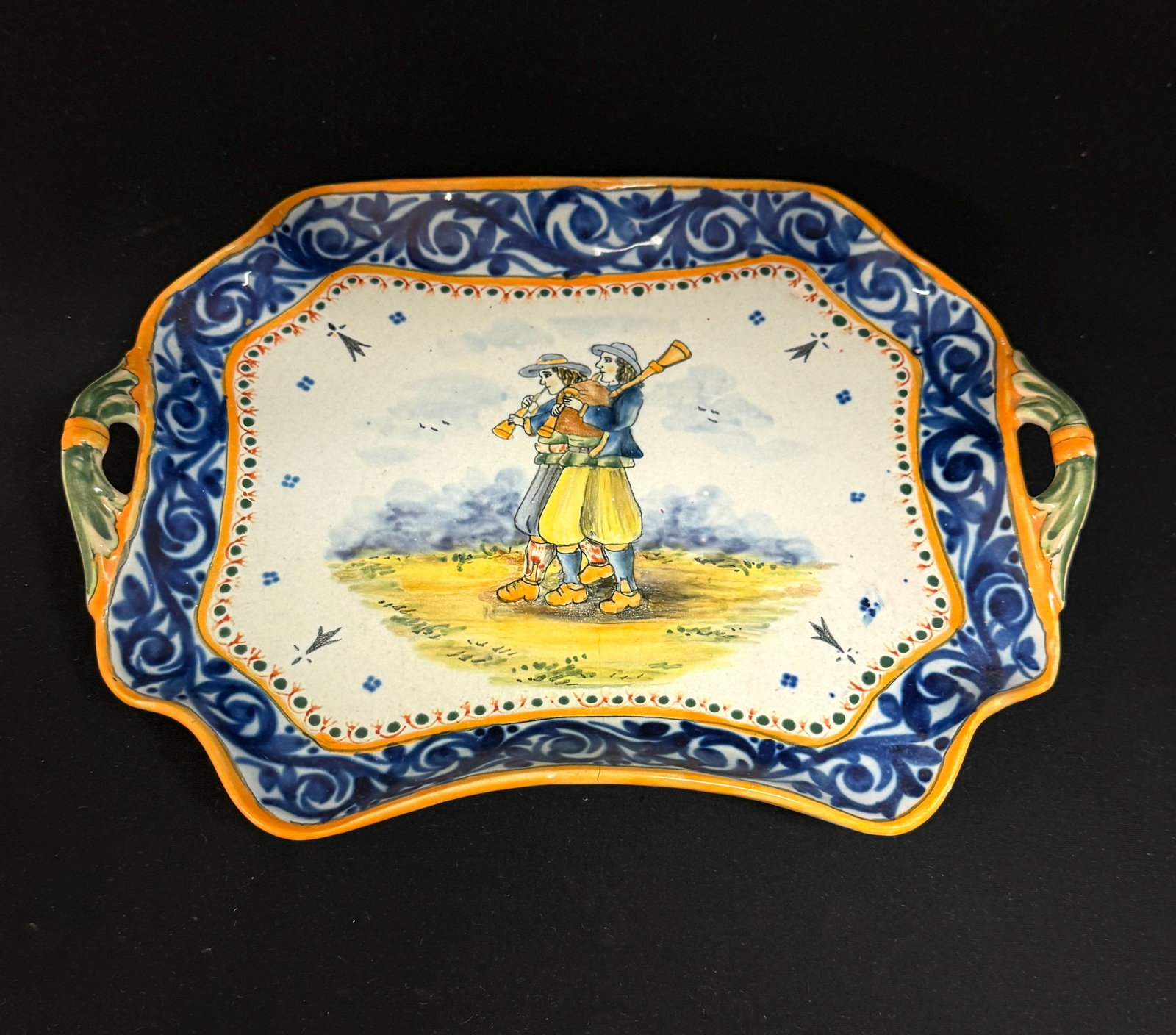 HB Quimper Rectangular Bannette: HB Quimper footed rectangular bannette with foliate handles, d?cor riche border, ermine tail, 4 dot motif framing a country scene of 2 Bretons playing a biniou and bombarde; length 11 1/2" circa