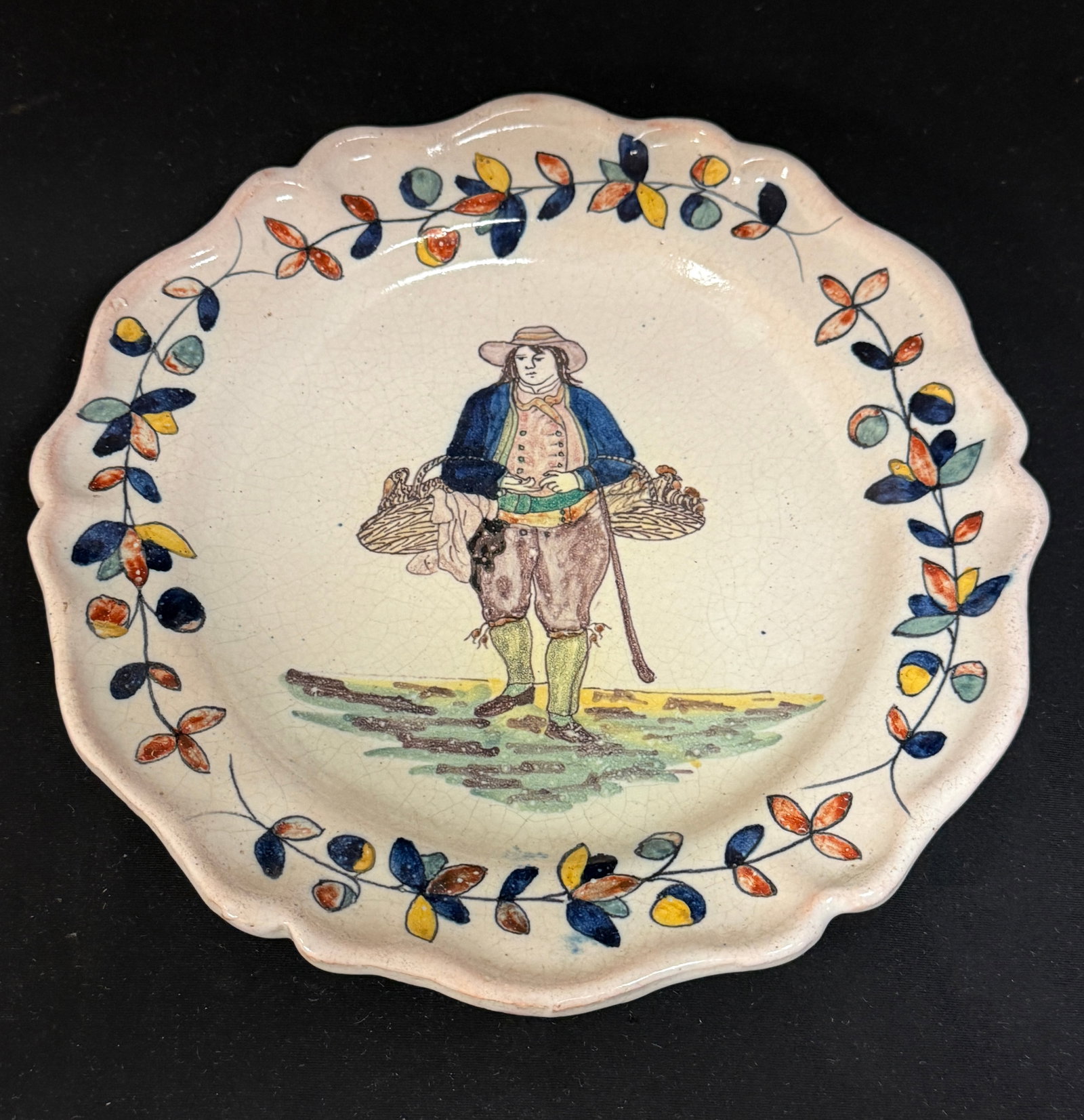 Malicorne Deep Plate: Malicorne deep plate depicting a Breton carrying 2 baskets of fowl bordered with traditional Malicorne border, signed PB; diameter 10" circa 1895 (pre lawsuit). CONDITION: Quimper has propensity to