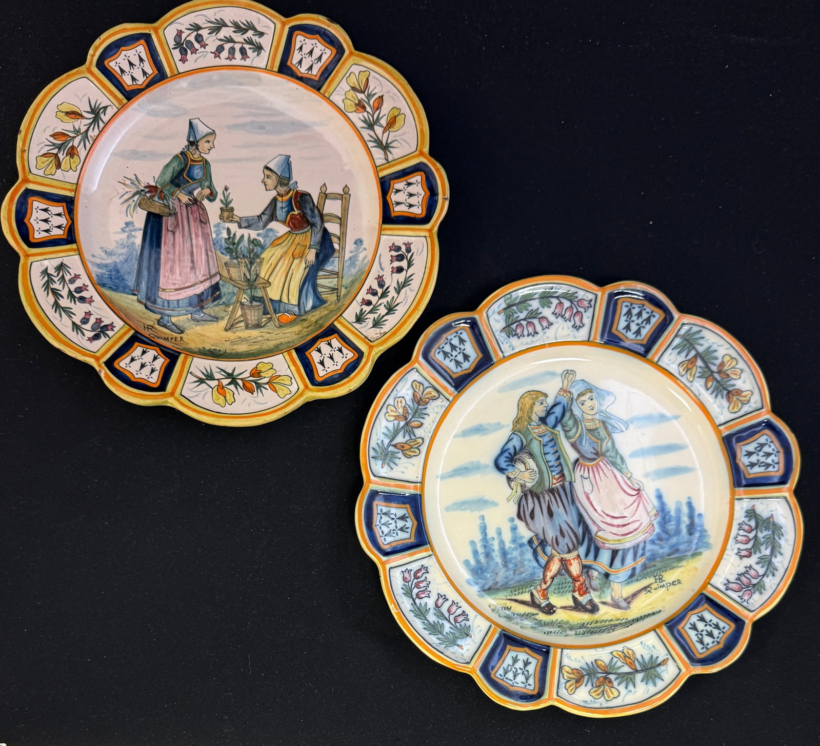 HR Quimper Scalloped Rim Plates: 2 HR Quimper scalloped rim plates decorated with ermine tails, panels of bruyere and ajonc sprigs, one plate with scene of Bretonne selling plants the other with newly wed couple dancing; diameter 9