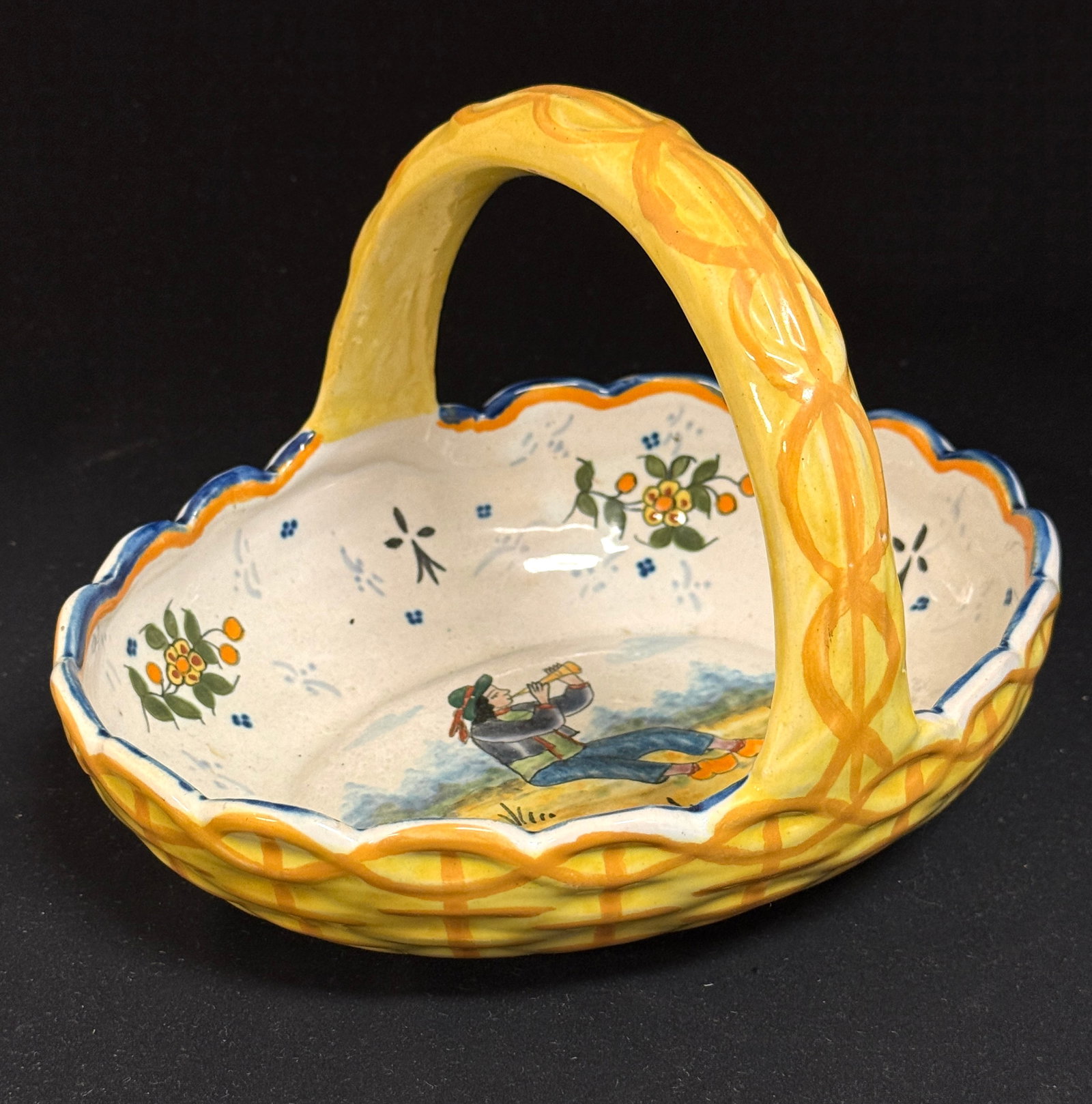 HB Quimper Basket: HB Quimper basket with handle and scalloped edges, interior scene of Breton seated and playing a bombarde, rim decorated with stylized ermine tail,4 dot motif and sprigs of flowers; ht. 6" circa