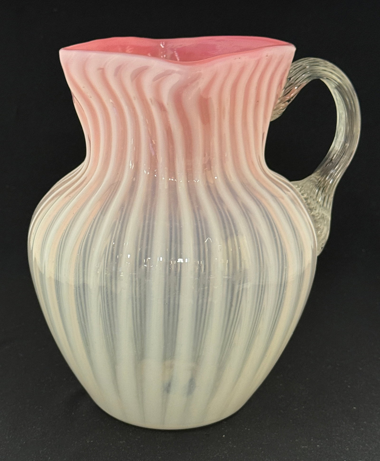 Pink Opalescent Water Pitcher: Pink vertical stripe opalescent water pitcher with reeded handle, 8 1/2" ht. CONDITION: no chips, cracks, repairs or material defects found, Jaremos attempts to call any material flaw that affects