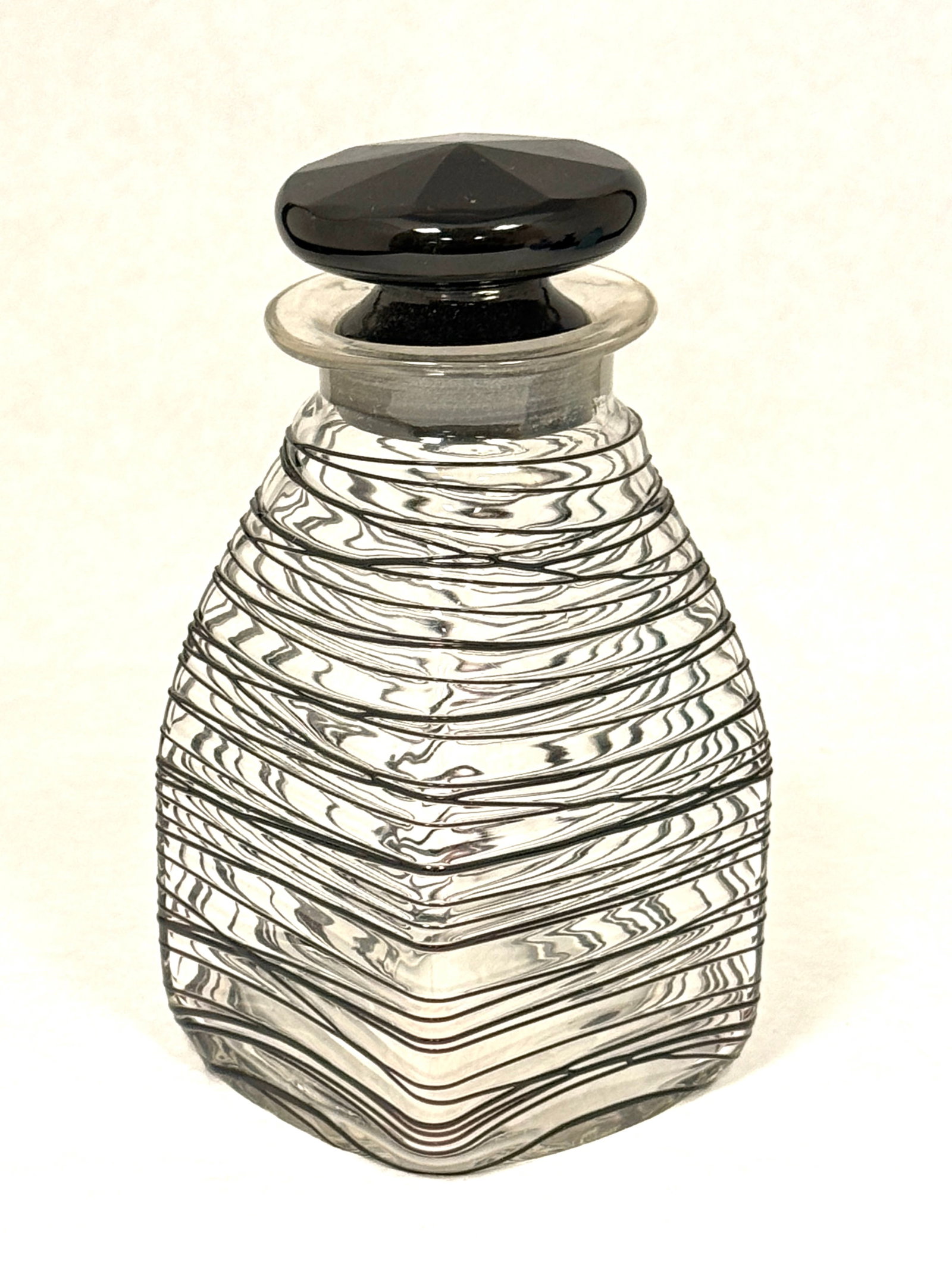Steuben Black Threaded Bottle: Steuben translucent glass bottle with overall black threading and a black stopper, 5 1/2" ht. CONDITION: very minor flake to the underside of the foot, see picture