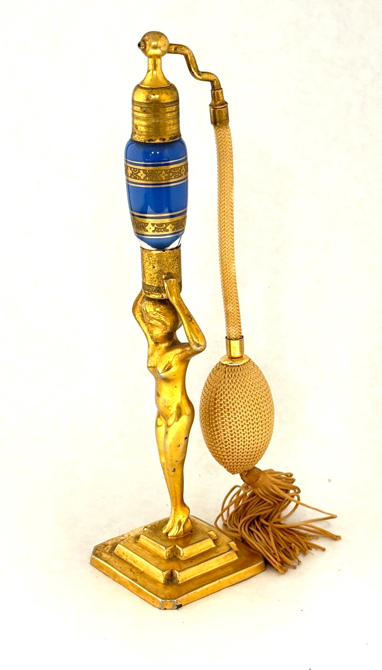 Volupte Blue Perfume: Volupte Blue Figural Perfume atomizer, female nude holding a blue opaline bottle with gilt bands, bottom stamped Volupte, 9 1/2" ht. CONDITION: no chips, cracks, repairs, or material defects found,