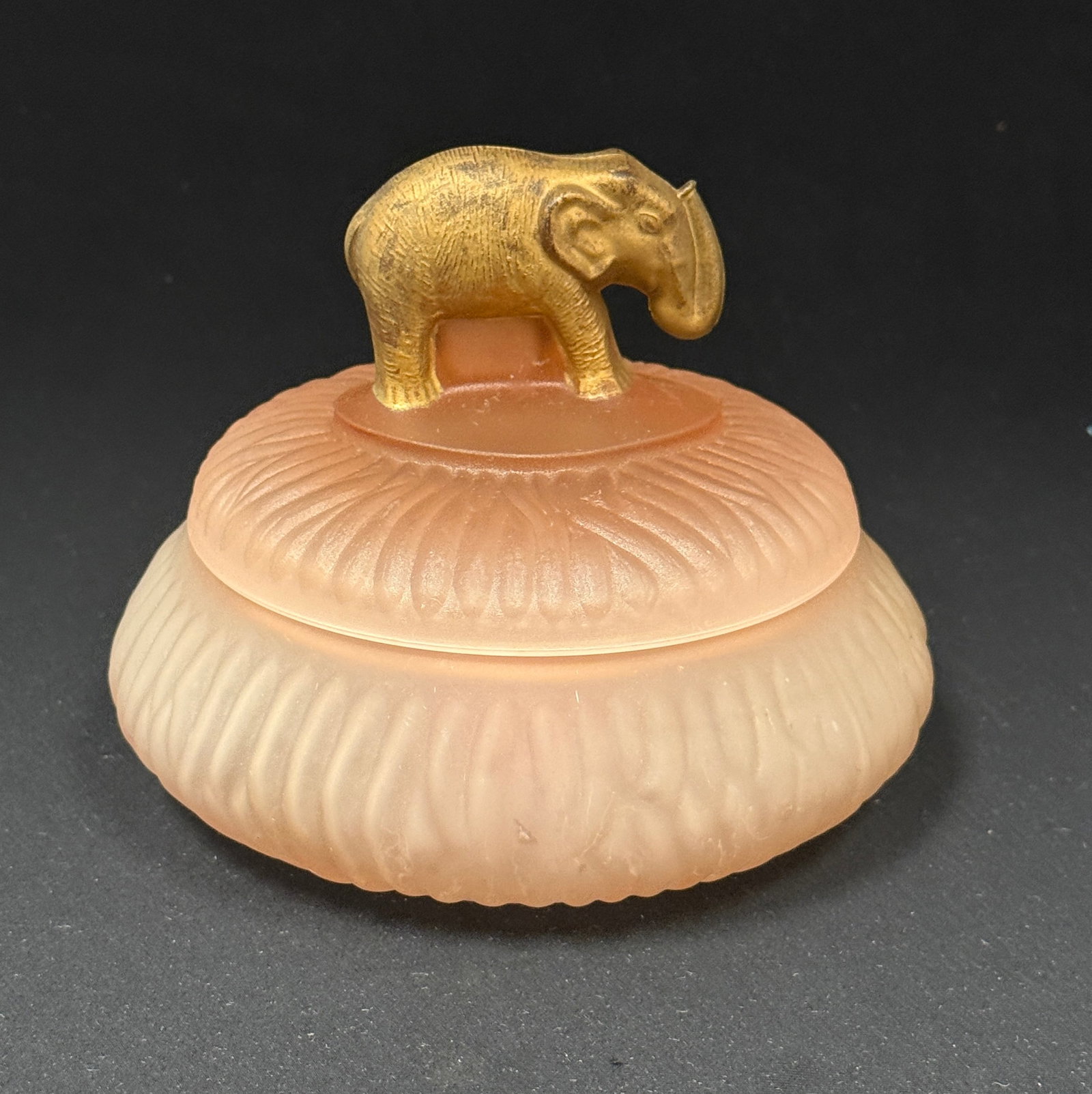 Pink Powder Box with Elephant: LE Smith pink drapery powder box with a gold gilt Elephant finial, 6" wide. LITERATURE: "Bedroom & Bathroom Glassware" by Whitmyer page 11. CONDITION: no chips, cracks, repairs, or material defects