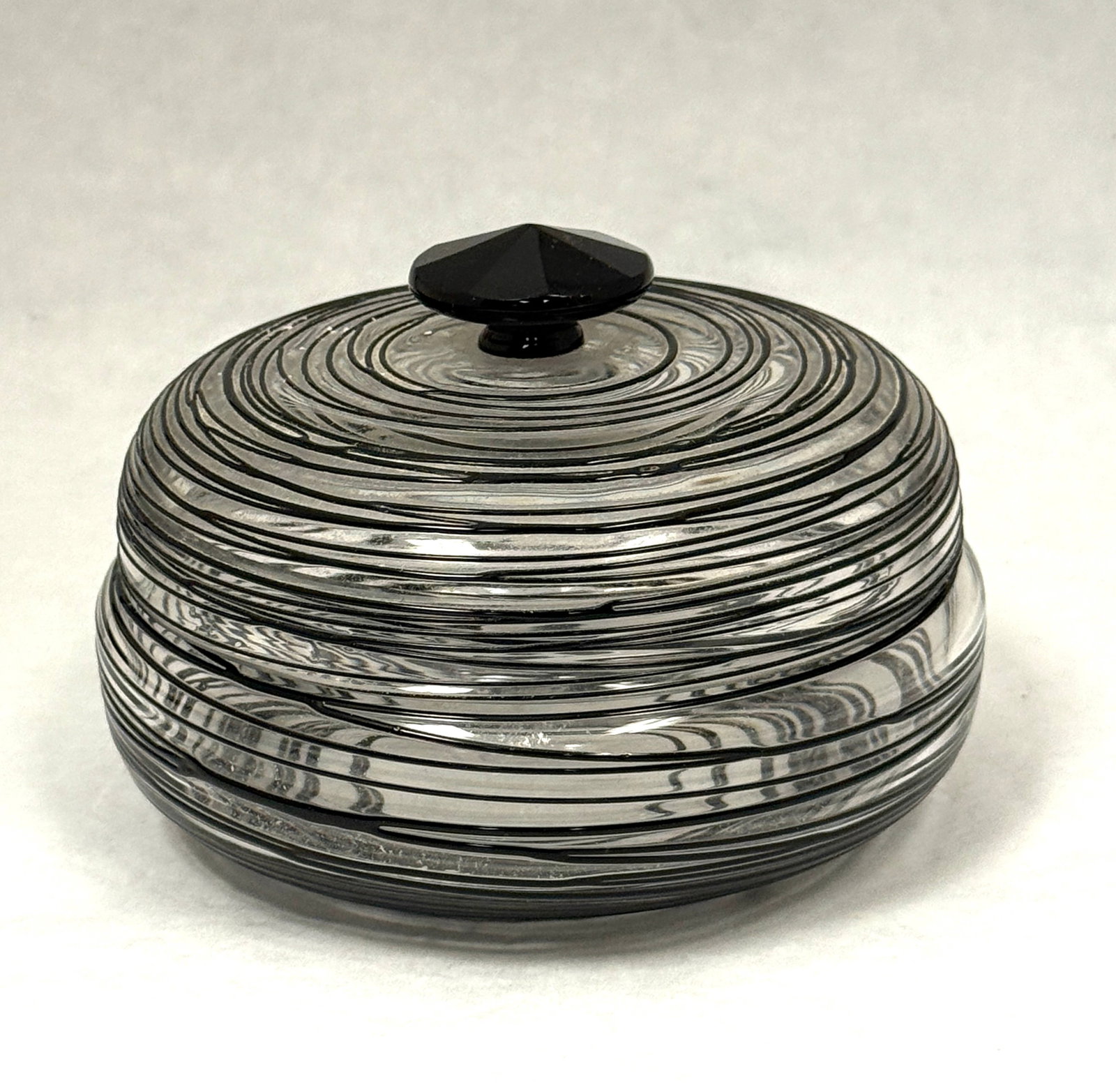 Steuben Clear and Black Box: Steuben translucent dresser box with mirror black threading and a faceted stopper, 5 1/2" wide. CONDITION: no chips, cracks, repairs or material defects found, Jaremos attempts to call any material