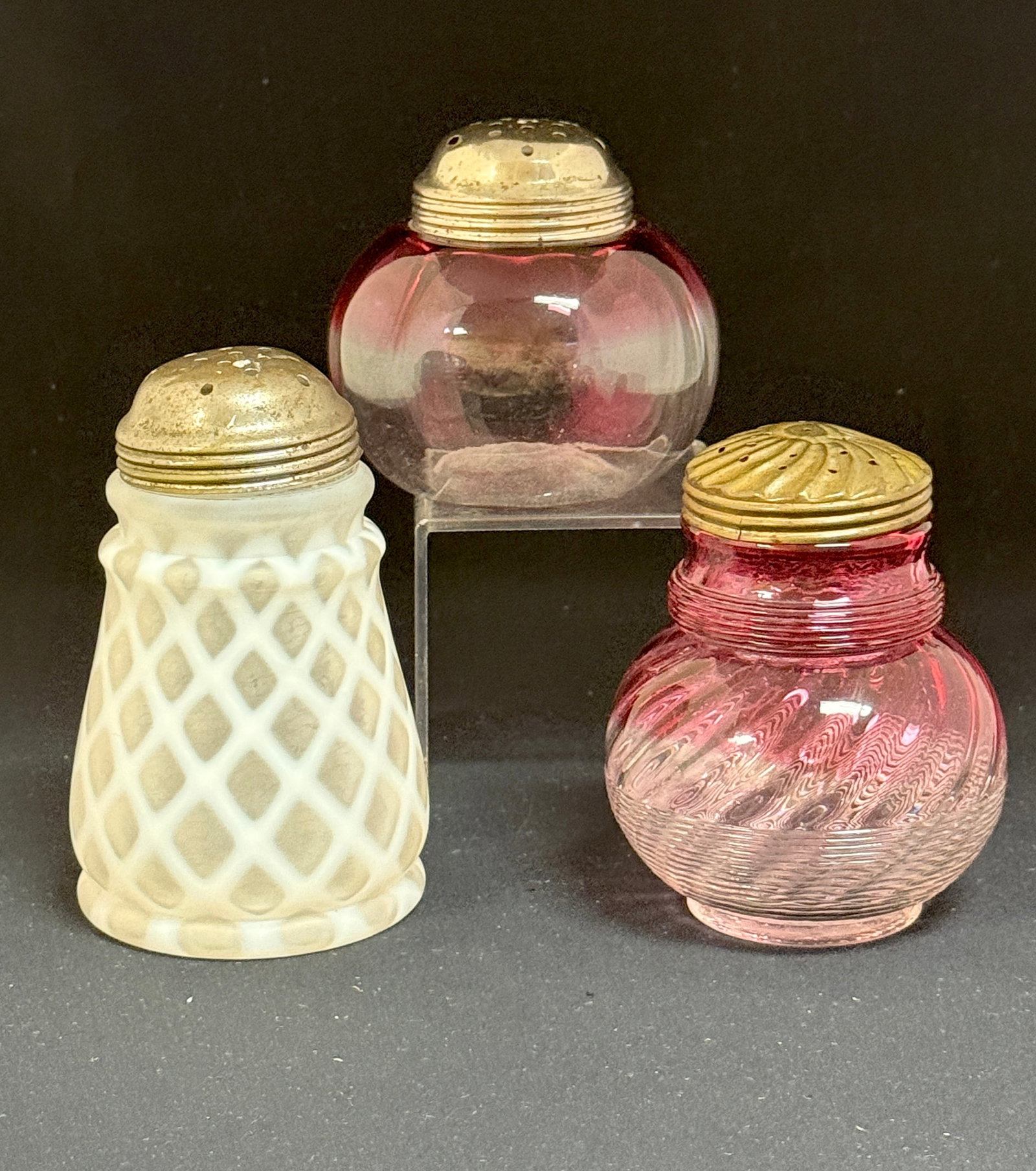 3 Victorian Sugar Shakers: 3 Victorian sugar shakers including 2 rubina and an opalescent lattice; ht. of tallest 5". CONDITION: no chips, cracks, repairs or material defects found, Jaremos attempts to call any material flaw