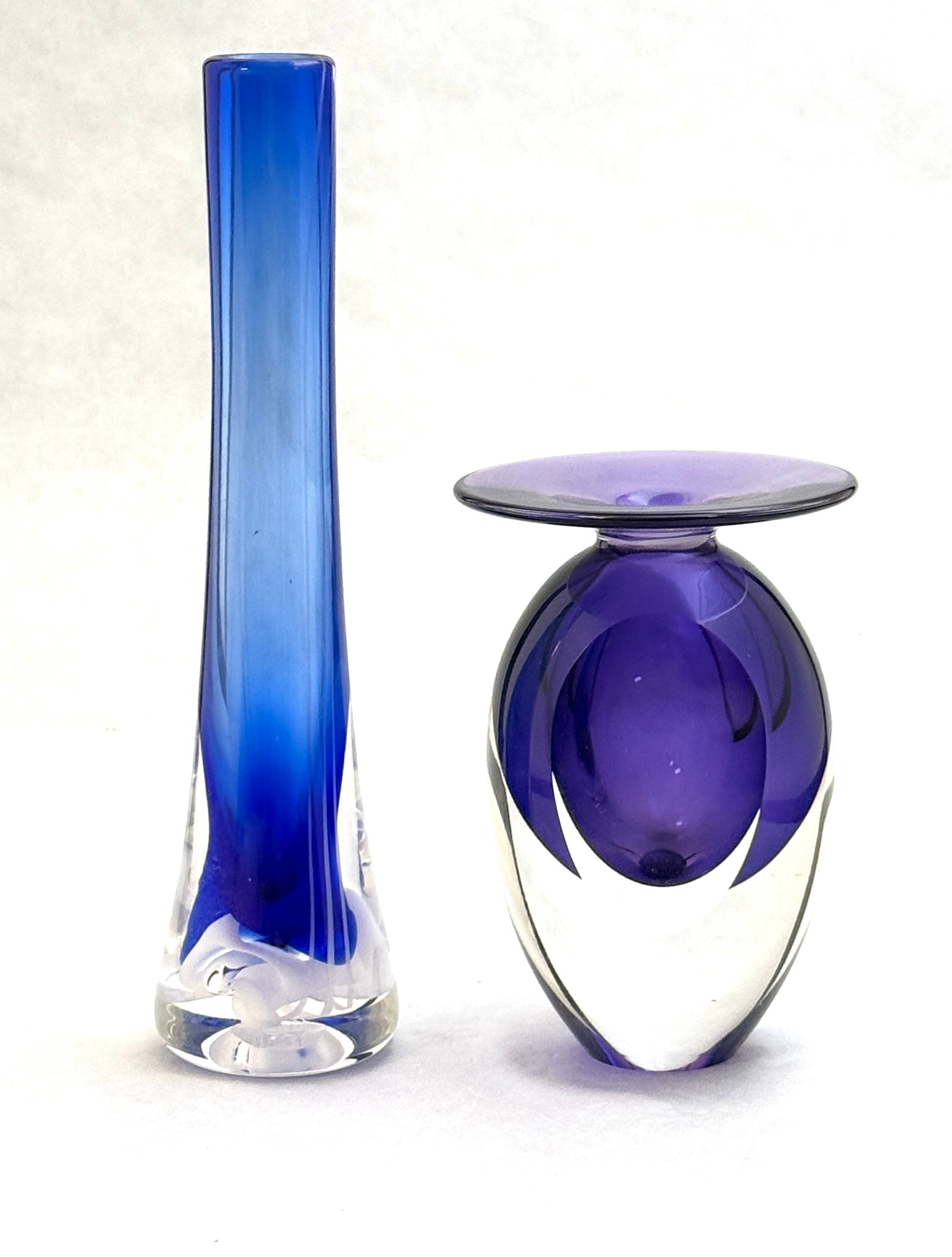 Two Art Glass Vases: Two Art glass vases including a signed Richard Jolley blue bud vase together with a signed purple Michael Trimpol vase with flat side, 9" ht. CONDITION: no chips, cracks, repairs, or material defects 