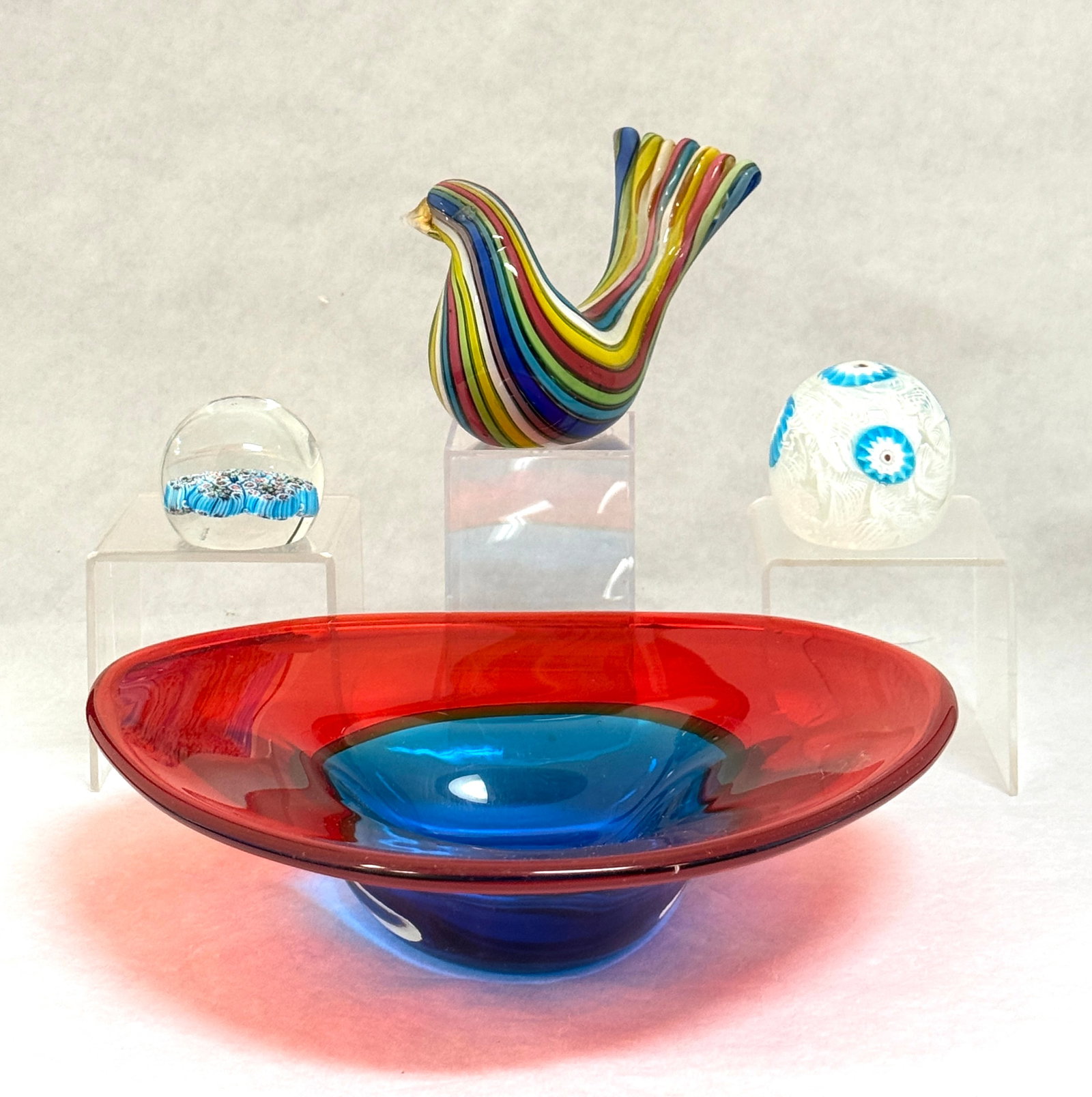 4 Murano Art Glass Items: 4 Murano art glass items including a red and blue bowl, a multi-colored striped bird, and 2 paperweights; largest diameter 9 1/2". CONDITION: no chips, cracks, repairs or material defects found,