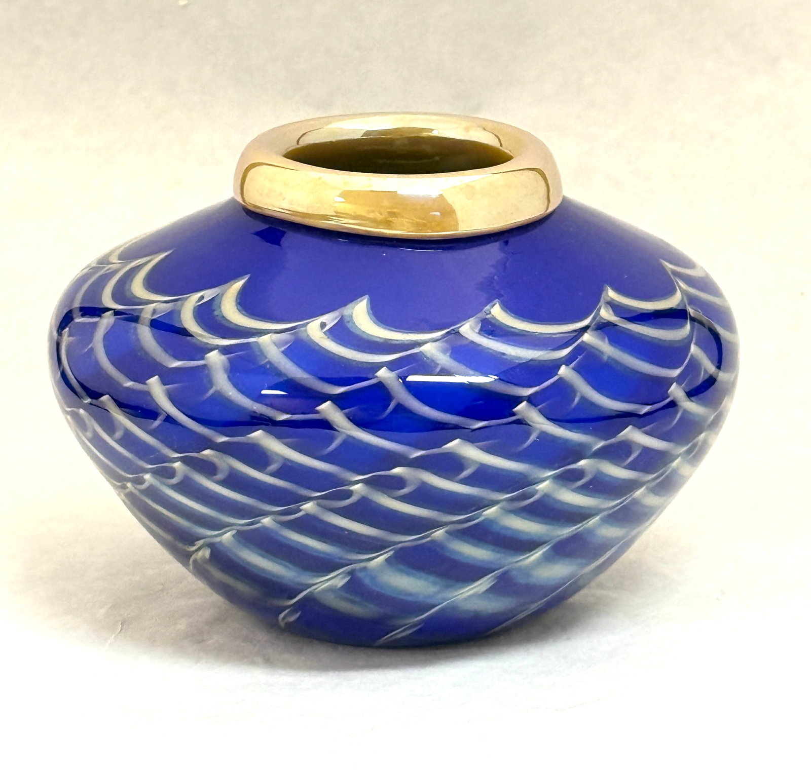Lundberg Squat Vase: Lundberg blue with gold waves and gold rim squat vase, signed S Lundberg Glass Art 2000 and with paper label; ht. 5". CONDITION: no chips, cracks, repairs, or material defects found, Jaremos attempts