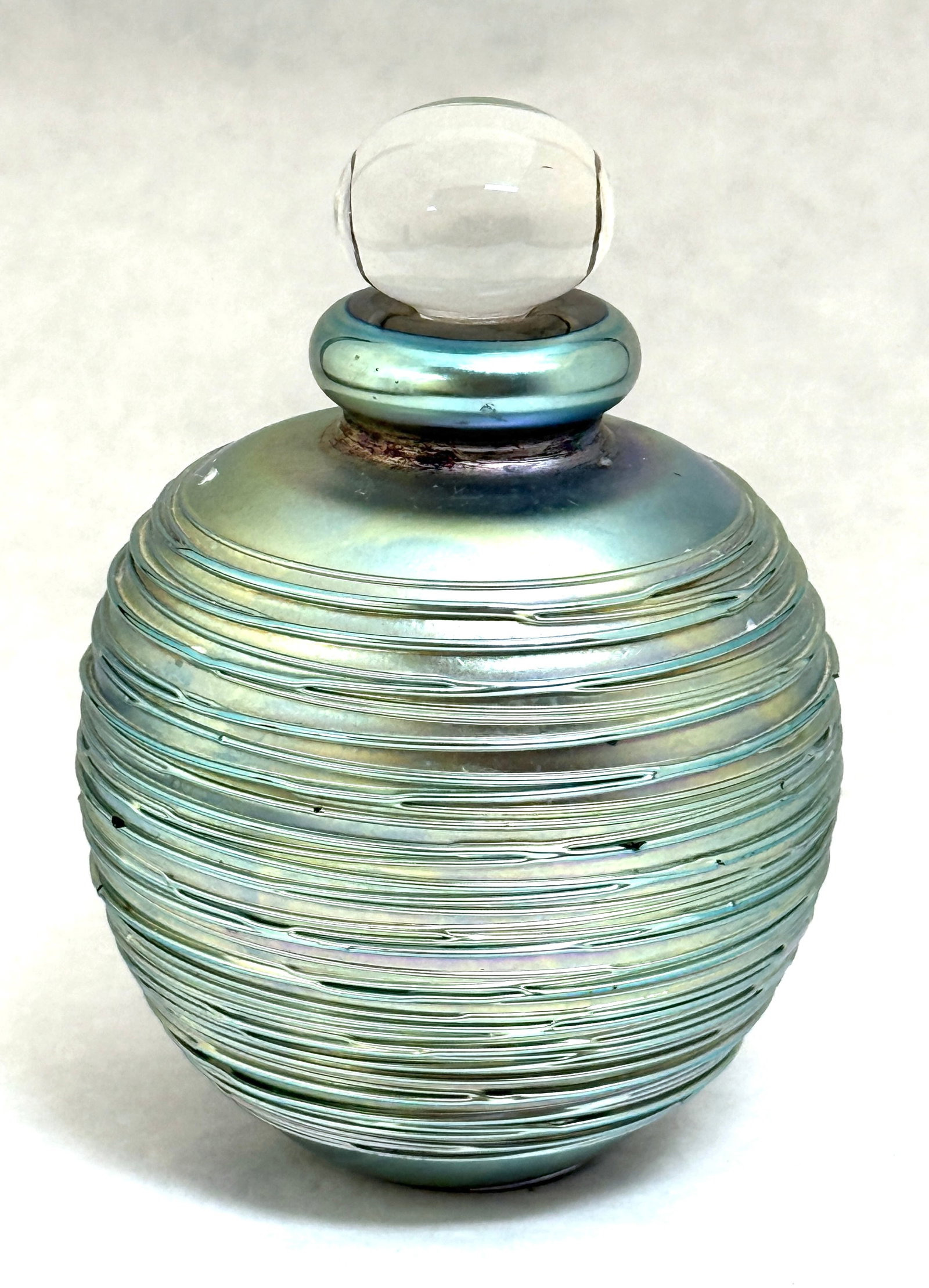 Eickholt Perfume Bottle: Eickholt iridized and threaded perfume bottle, signed Eickholt 1986; ht. 5" with dobber. CONDITION: no chips, cracks, repairs, or material defects found, Jaremos attempts to call any material flaw tha