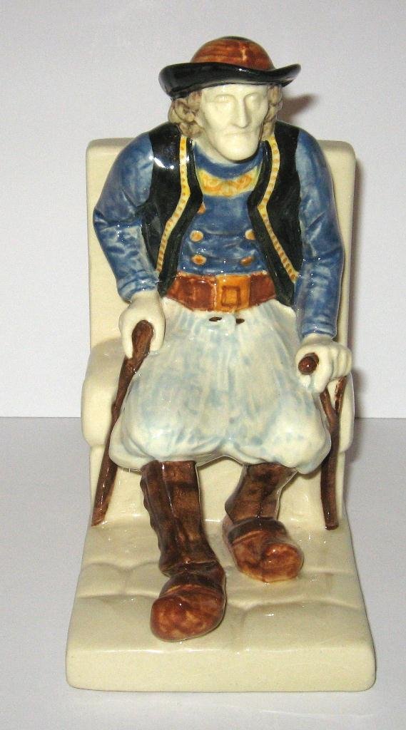 HB Quimper "Bouvier" Breton bookend,: with seated figural of old Breton with canes in traditional costume by artist Bouvier. 6 1/2" ht. c.1930.