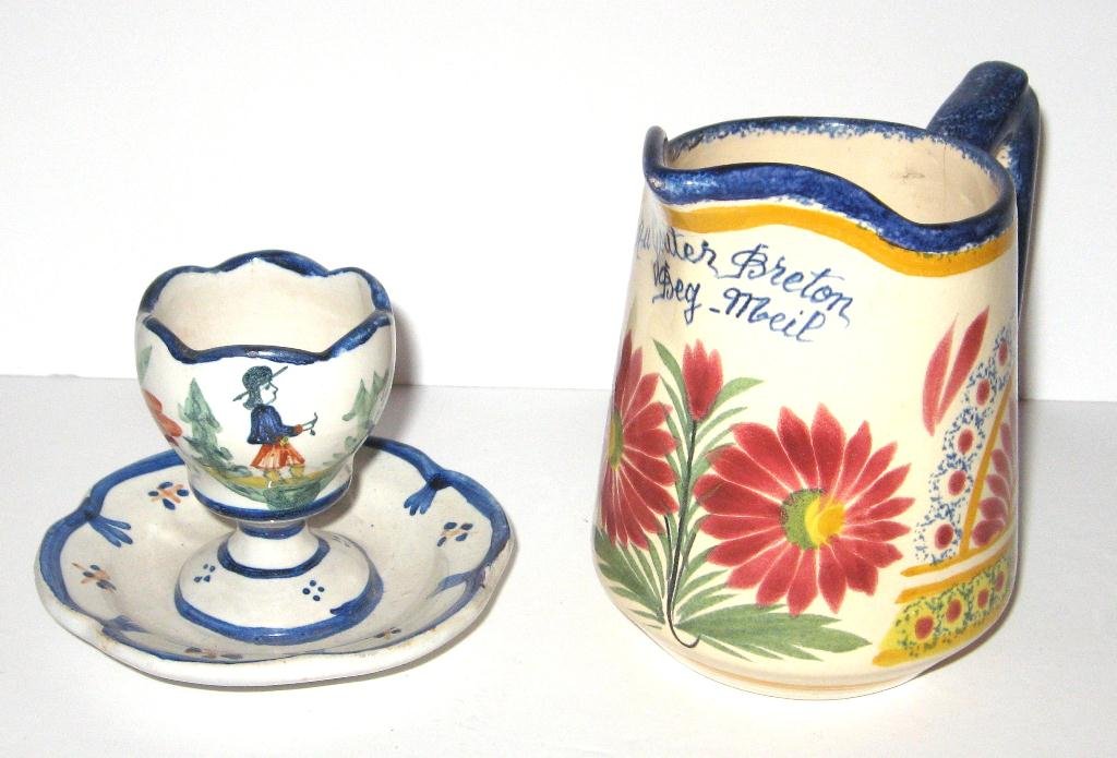 Henriot Quimper "Ivoire Corbeille" honey pitcher and HB: pitcher having sponged and a la touche motifs and French phrase, egg cup with attached plate has Breton motif. 4.5" ht. c.1930-1940.