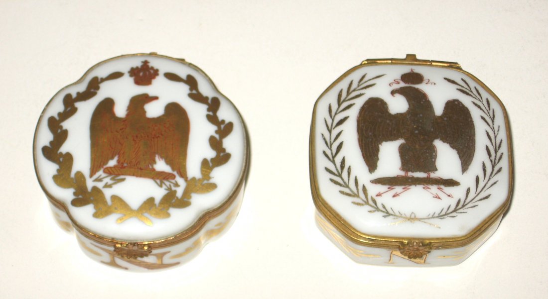 Pair of Continental pill boxes,: each in white porcelain decorated with red over gold eagles and a large N for Napoleon on the front, one with interlocking LL the other with an N under mission, 2 1/4" wide.