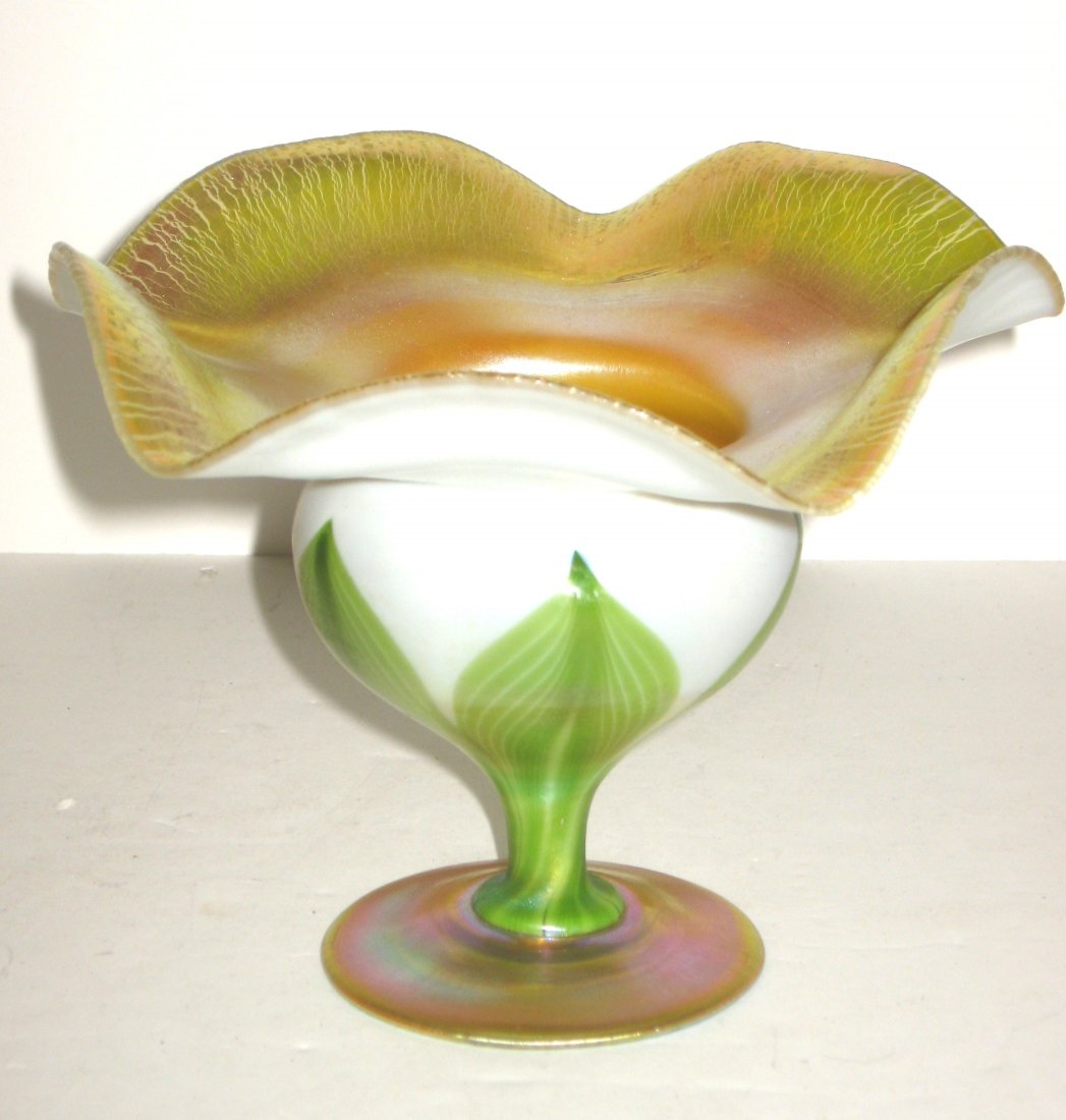 Tiffany flower form glass coupe,: footed compote form with a spreading scalloped rim in opal glass decorated with green pulled leaves and adorned with a bright gold interior, signed 4140J L. C. Tiffany-Favrile, 5" ht.
