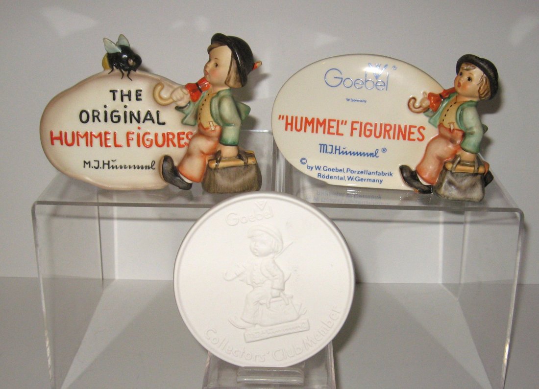 Three Hummel advertising signs,: including two Hummel number 187 retailer signs one with a TMK2 full bee mark the other with a TMK 5, together with a Collectors Clum Member plaque.