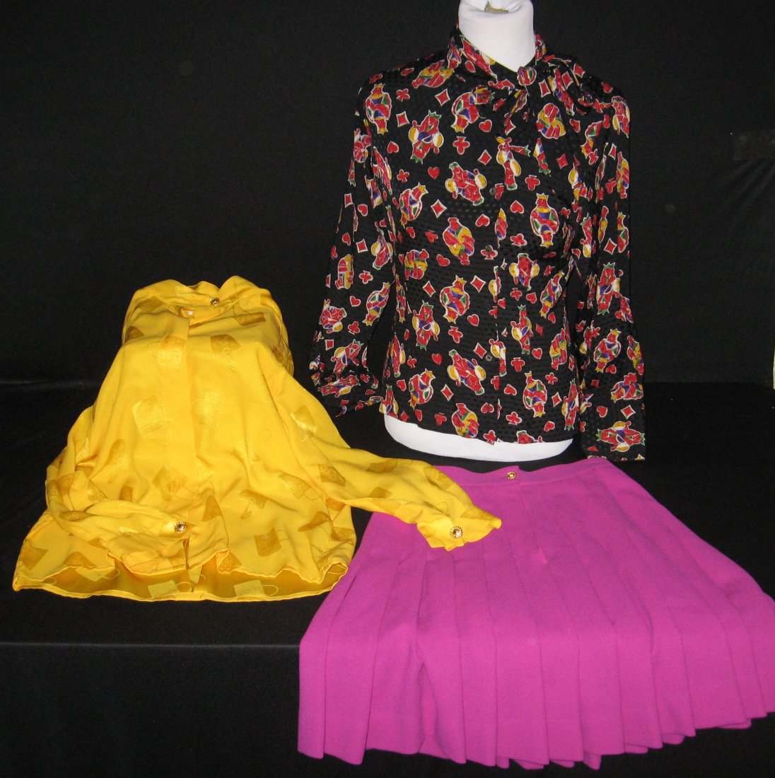 Group of Celine designer cloths,: Including a purple pleated skirt with gold tone buttons approx size 36, together with marked 36 yellow silk top and black top in a red, green, and yellow playing card design, approx size 36.