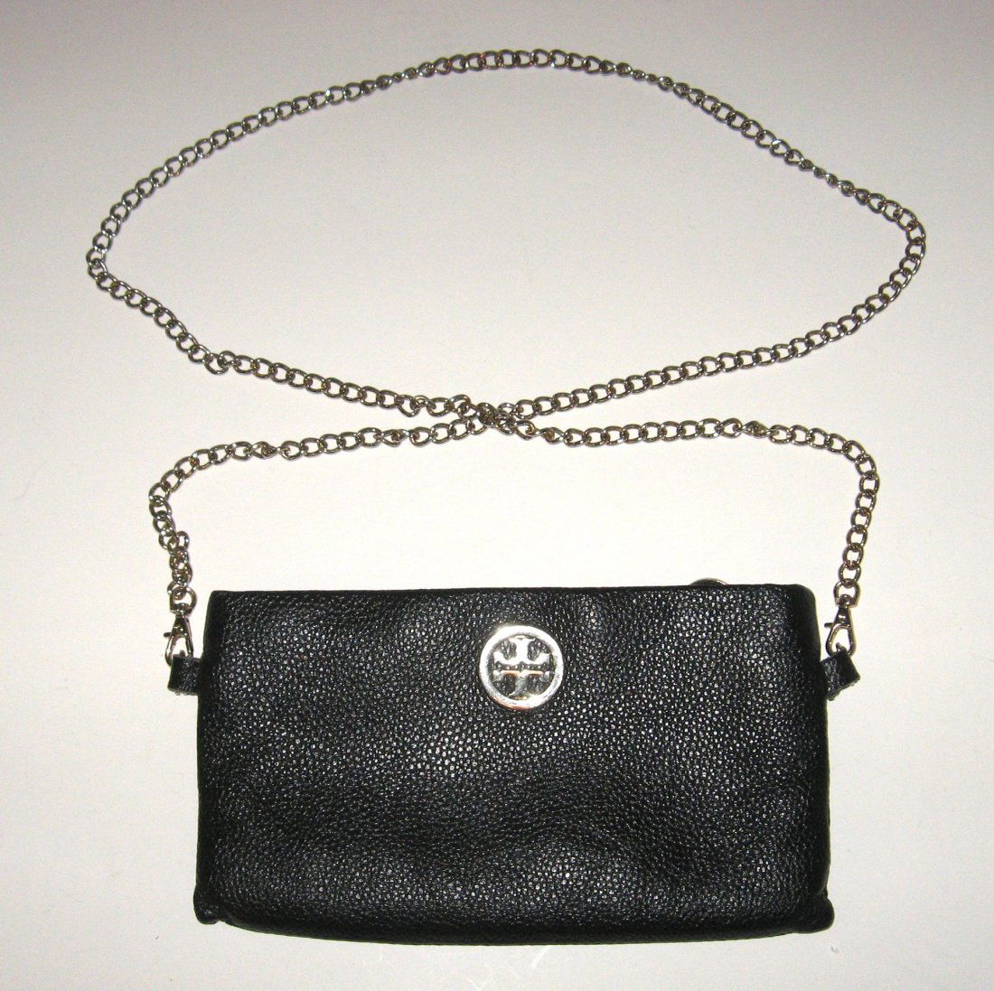 Tory Burch black leather shoulder clutch,: rectangular black leather clutch with silver emblem and long shoulder chain, with triple sectional interior of credit card caddy and zippered compartment, 9' long by 5" ht. without handle.