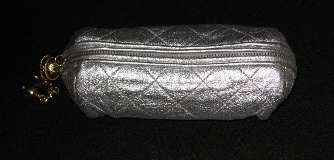 Chanel silver evening bag,: tube form in a quilted silver cloth adorned with a gold tone and crimson beaded tassel zipper pull marked with the double CC, marked on the interior Chanel Made in Italy, 6" long by 3 1/2' ht.