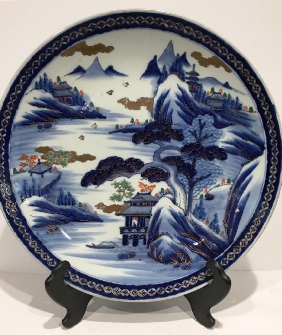 ANTIQUE IMARI CHARGER: POLYCHROME- (GOSAI), THE CENTRAL ROUNDEL CONTAINING GRADEN SCENES, LAKES, MOUNTIANS, BIRDS, TREES AND PAGODAS. THE OUTER RIM HAS GOLD, COLBALT BLUE AND LIGHT BLUE GEOMETERIC DESIGNS. CIRCA 19th CENTUR