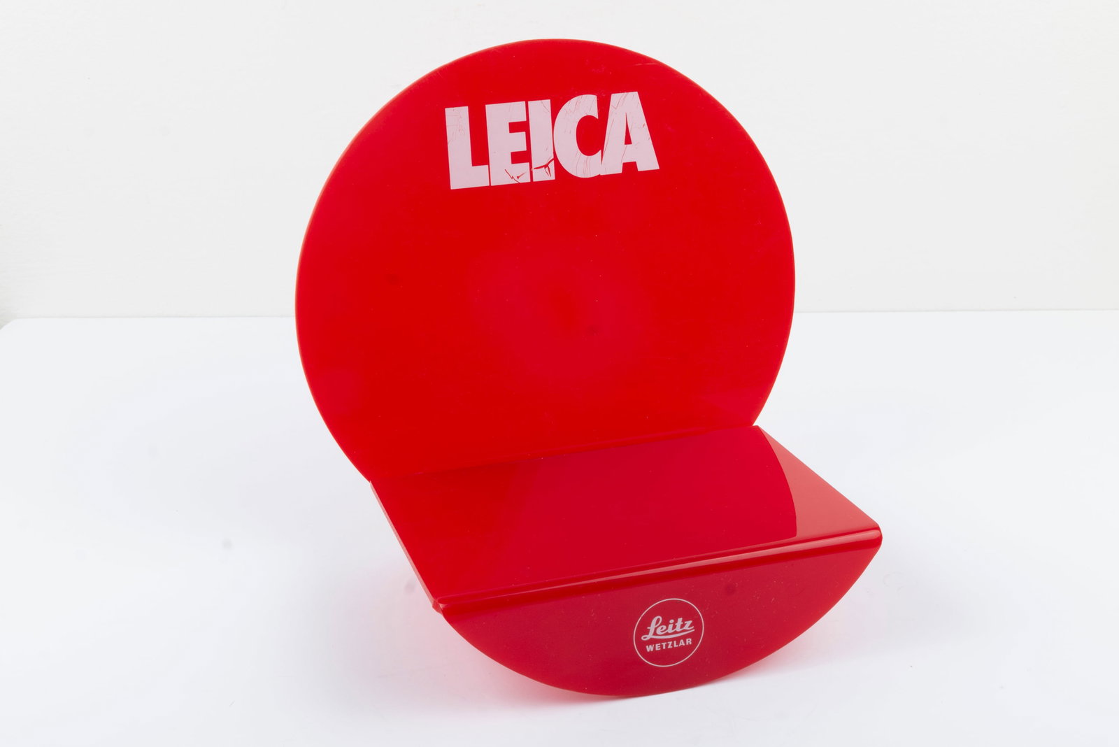 Leica plastic display stand: Leica plastic display stand, in two parts, with circular back.Condition: Excellent ++