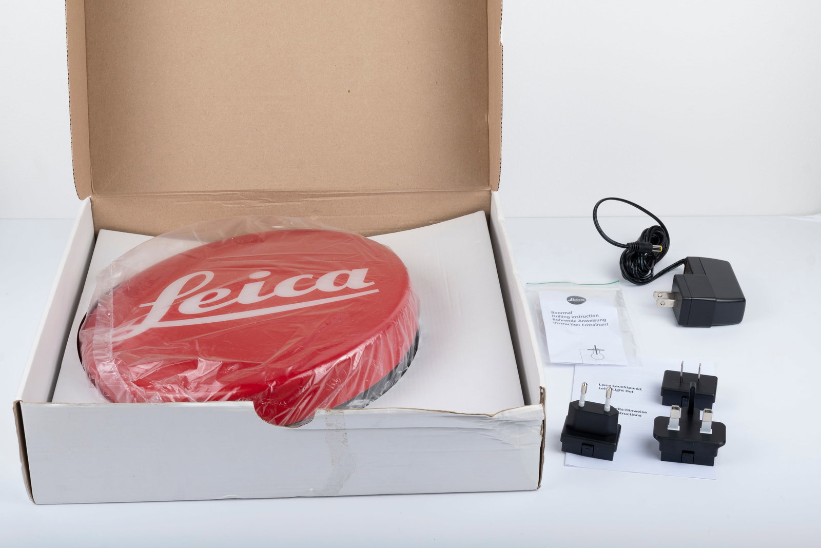 Leica Red Dot lighted sign: Leica Red Dot lighted sign, complete in its box and with multiple power adapters, measuring 10" in diameter. Unused, but with a small crack in the plastic.Condition: Near Mint