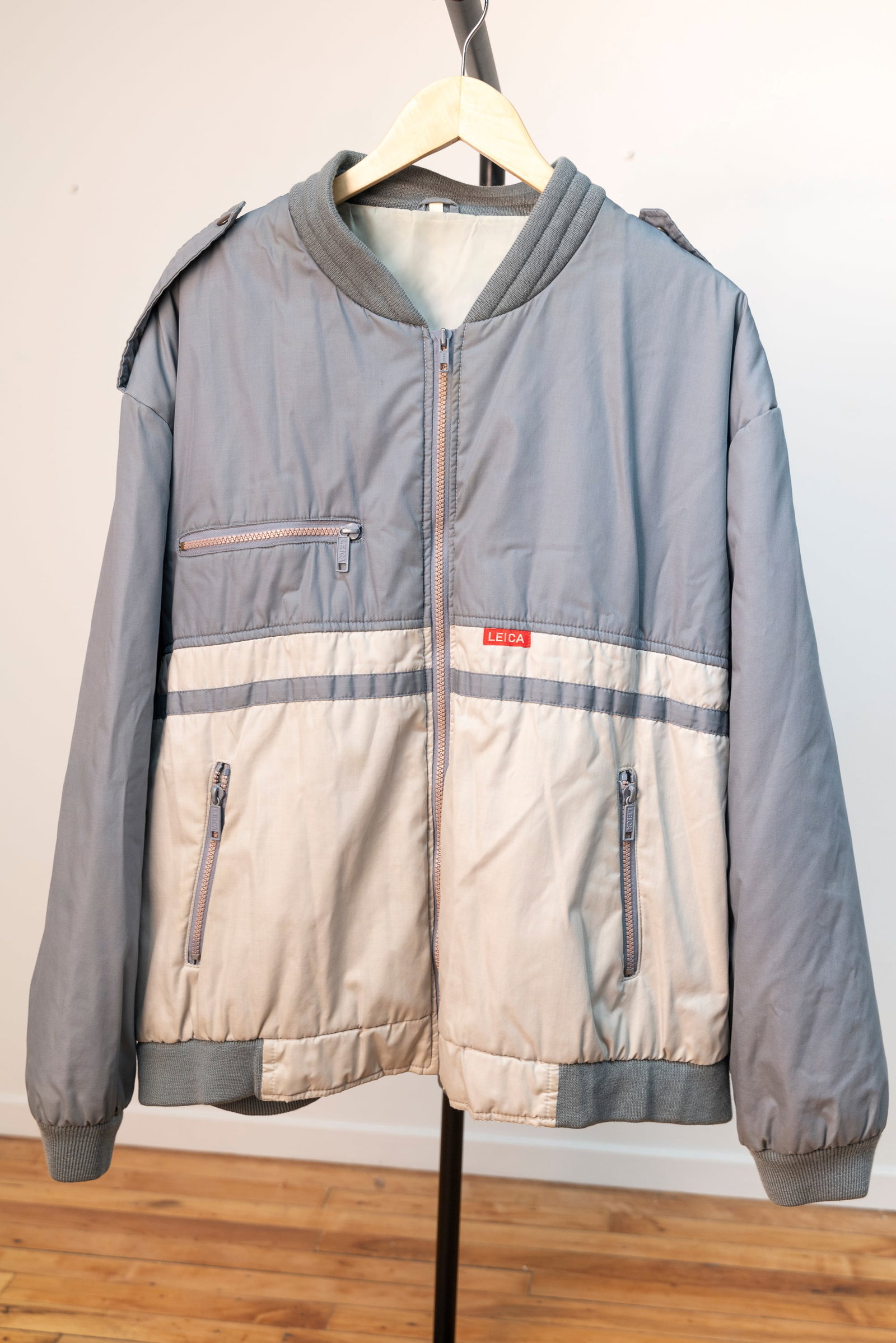 Blue-Grey Photographer's Jacket: Blue-Grey Photographer's Jacket in "XL" size, with "LEICA" brand lettering on chest and on the zipper pulls. The length is 28", the chest 50", the sleeve length 33" and the back width dimension is