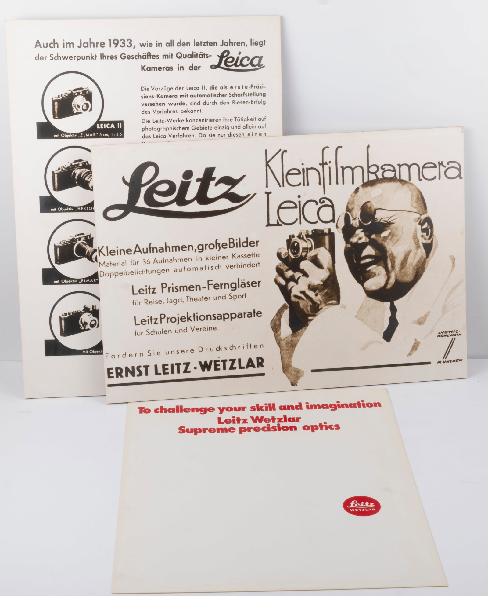 Two reproduction Leitz advertisements: Two reproduction Leitz advertisements on Masonite measuring approximately 15 3/4" by 11" along with and a brown Leica counter mat, measuring approximately 12" by 16" and a plastic ad card reading "To 