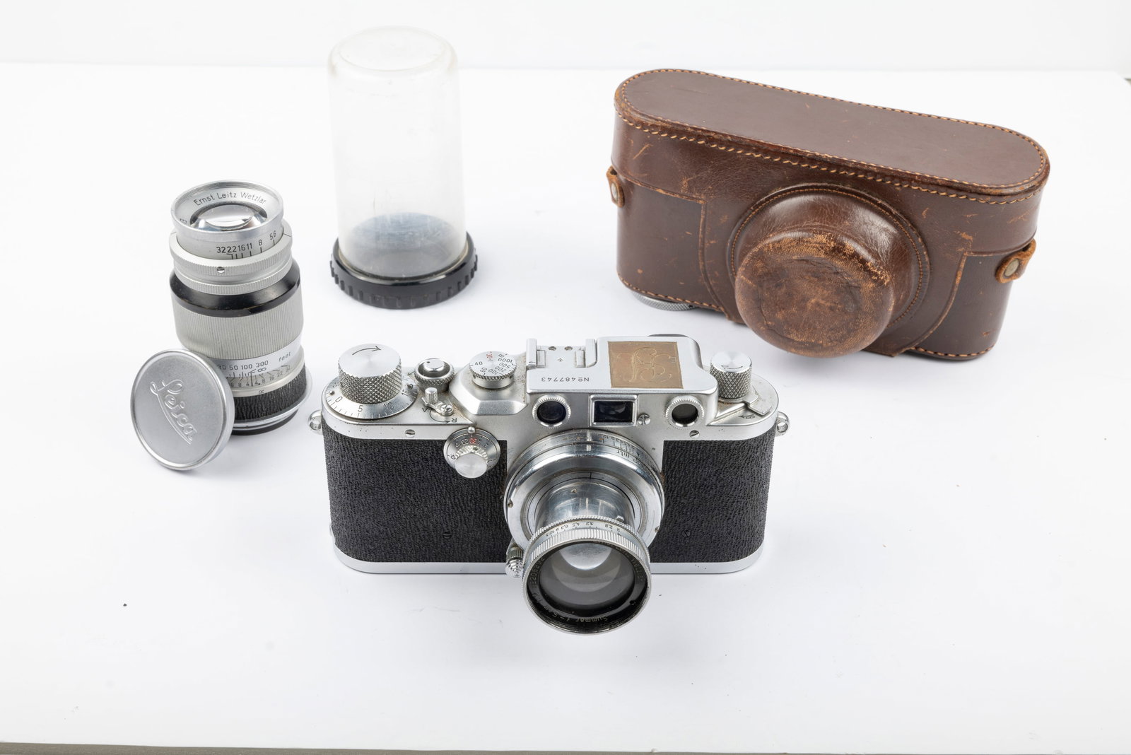 Leica IIIc "Sharkskin" Nr. 487743: Leica IIIc "Sharkskin" Nr. 487743 and 50mm Summar f2 Nr. 206292 and 90mm Elmar f4 Nr. 698778 in display container and lens cap. The camera top has been engraved "RS" and there is a hand-engraving on t