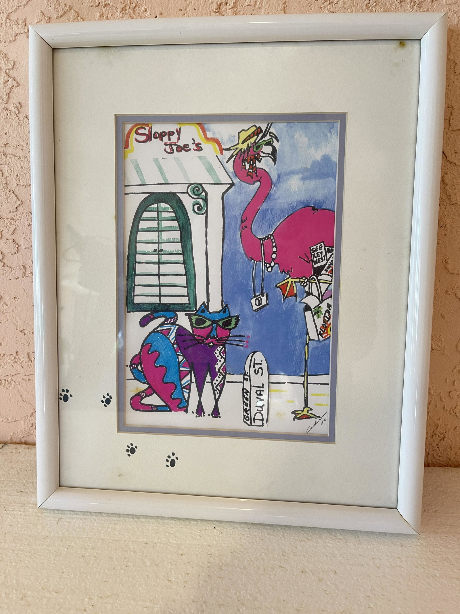 WHIMSICAL SIGNED SLOPPY JOES ART: WHIMSICAL SIGNED SLOPPY JOES ART signed by artist. A cat and a pink pelican visit the famous Sloppy Joes on Duval in Key West - Open since 1933. About 12 inches tall framed. NOTE ON ALL SIGNED LITHOS: