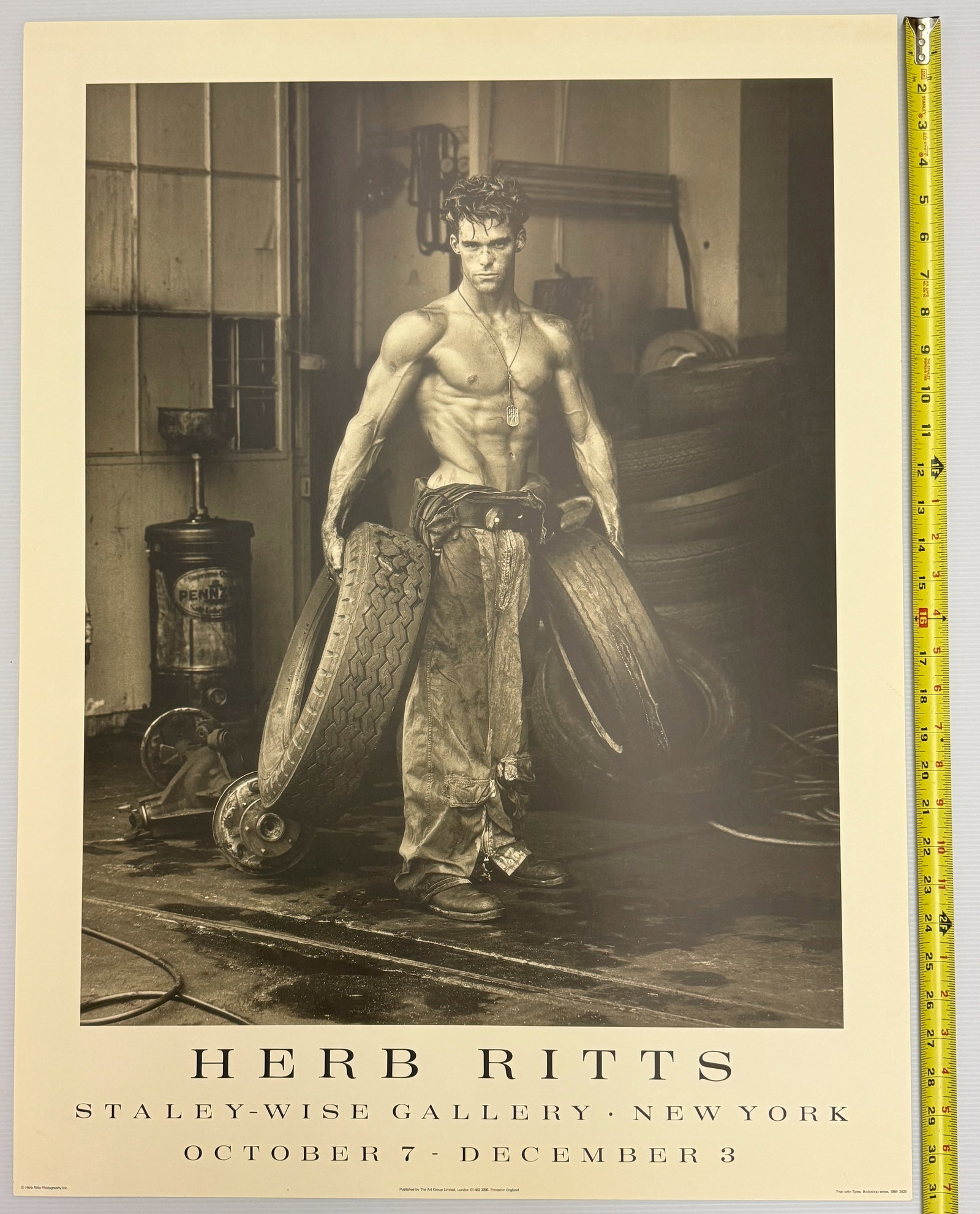 Fred with Tires by Herb Ritts - 1988: The image is a vintage exhibition poster featuring the iconic photograph "Fred with Tires" by American fashion photographer Herb Ritts. The poster advertises a 1988 exhibition at the Staley-Wise