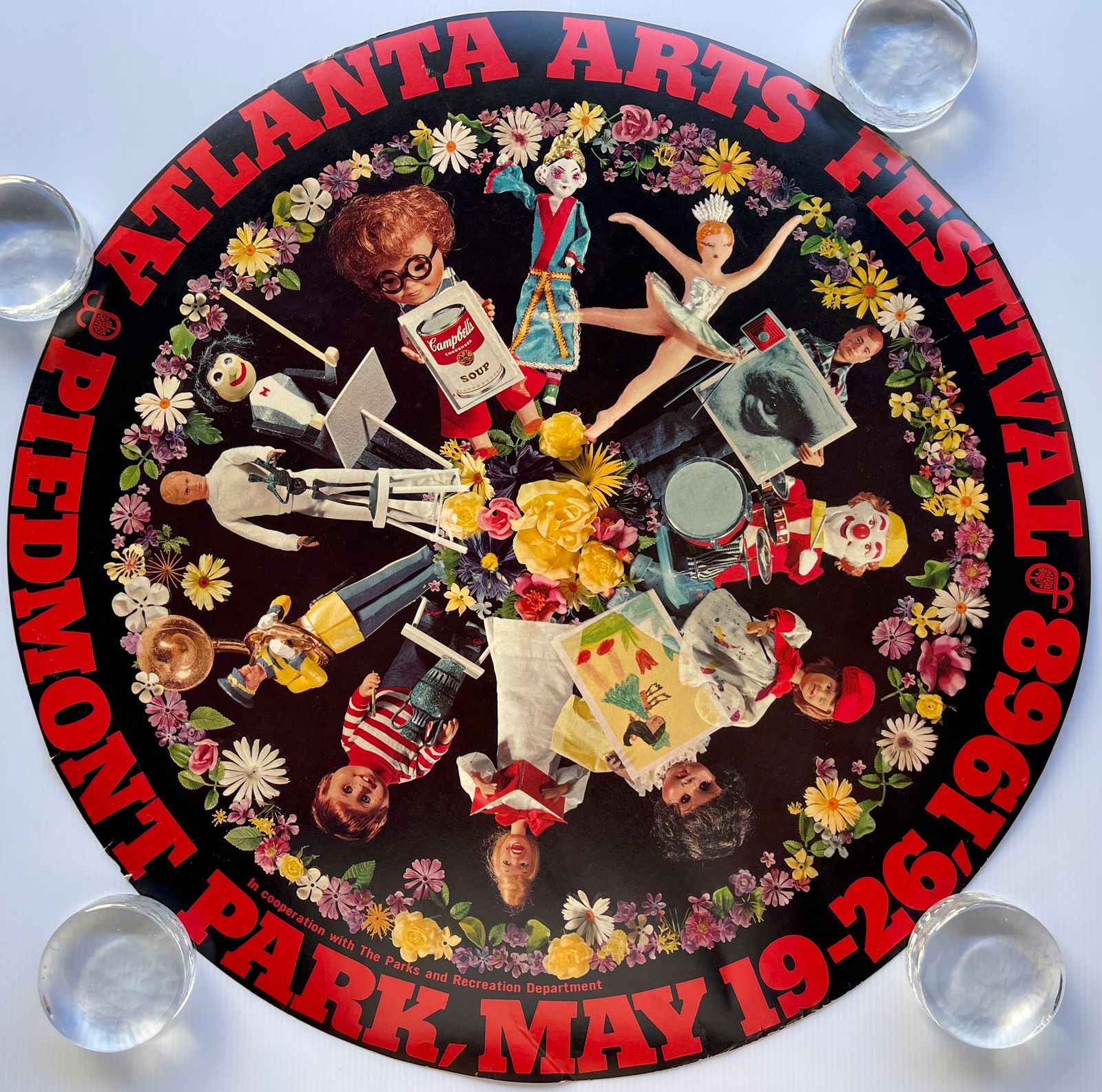 1968 Atlanta Arts Festival: The image shows a poster for the Atlanta Arts Festival, which took place at Piedmont Park from May 19–26, 1968. The poster has a circular design, featuring text around the border and various dolls a