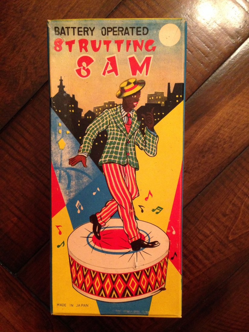 BATTERY OPERATED STRUTTING SAM - TIN TOY: BATTERY OPERATED STRUTTING SAM - TIN TOY. Near Mint. Japanese. Original Box. Nice lithography around base and overall a bright, clean, shiny toy. Includes very colorful original box. Condition (Excell